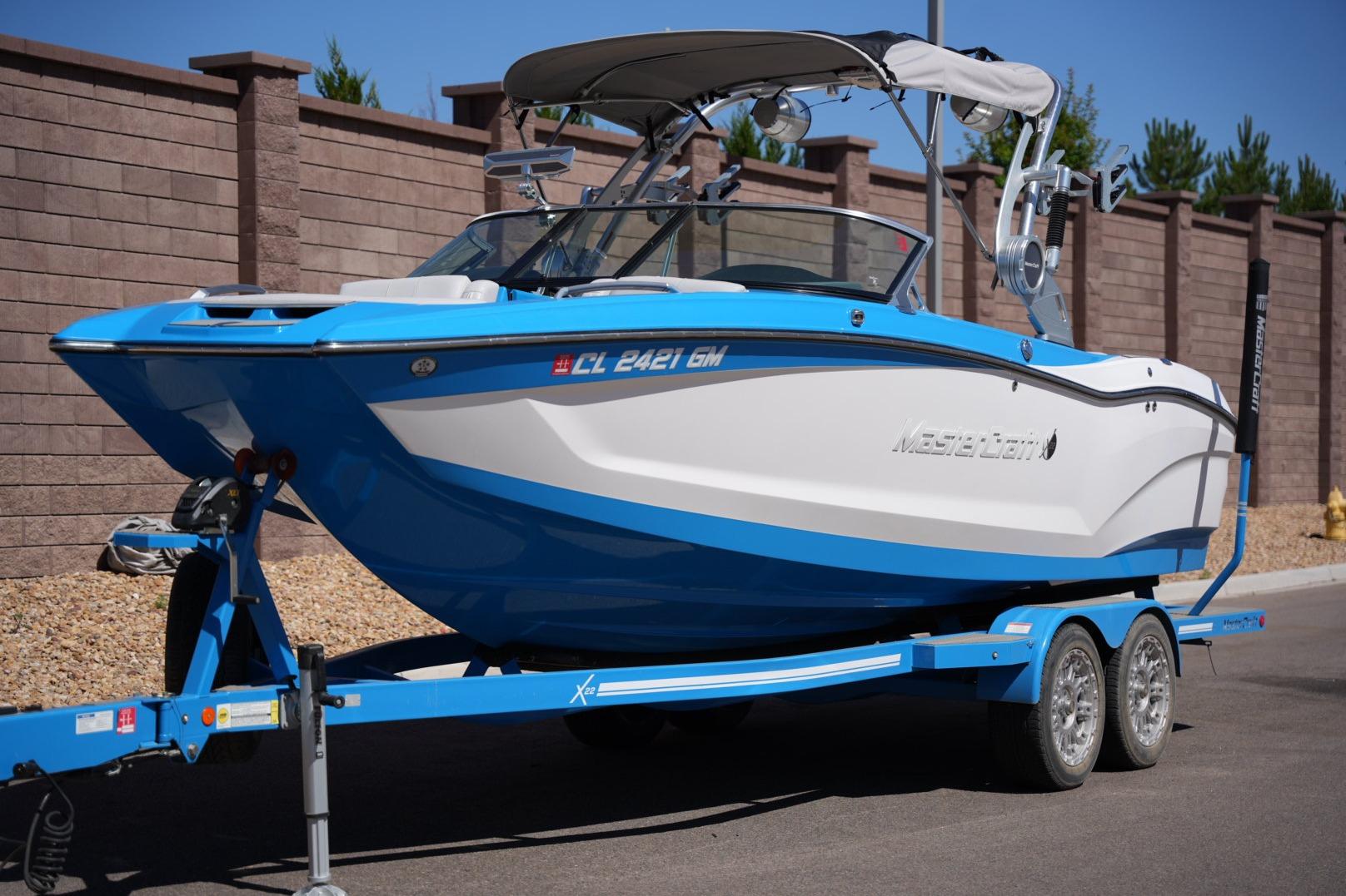 2020 MasterCraft X22 boat on trailer, blue and white design, parked outdoors.