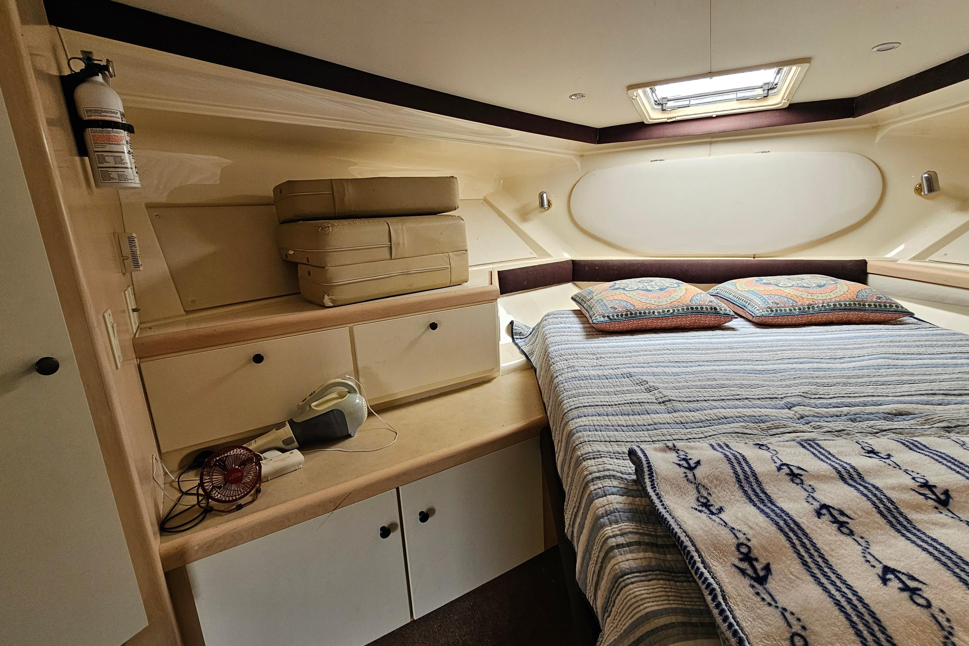 Cozy cabin interior of 1999 Carver 350 Mariner with bed, storage, and decor.