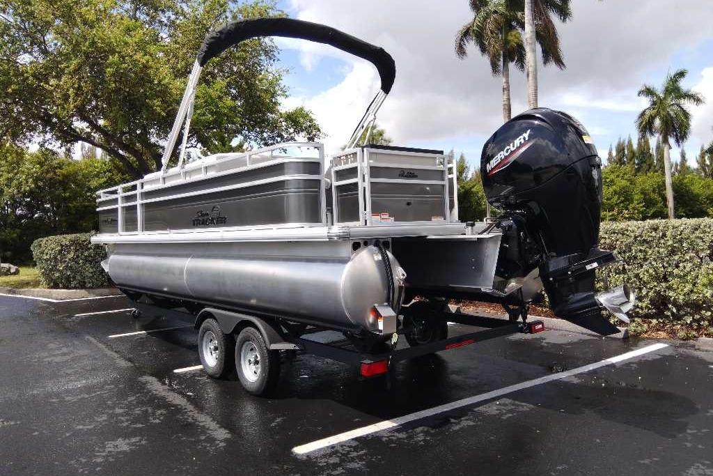 2026 Sun Tracker Fishin' Barge 22 DLX pontoon boat on trailer in parking lot.