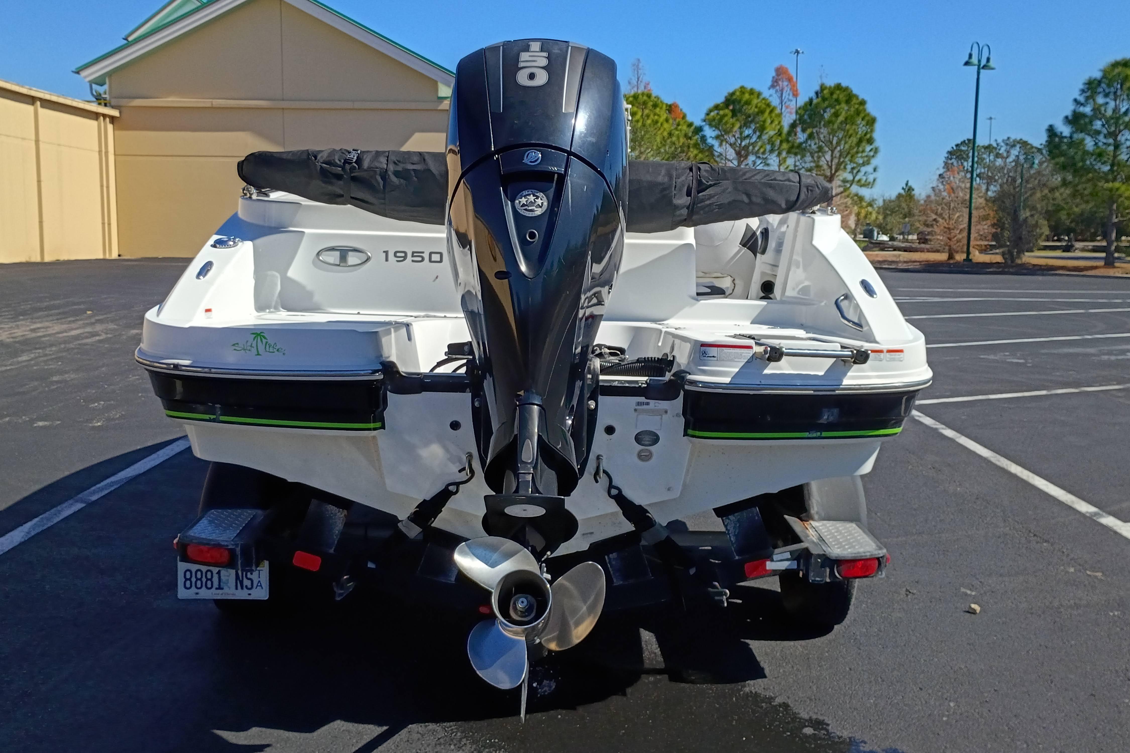 Rear view of a 2017 Tahoe 1950 boat with an outboard motor in a parking lot.