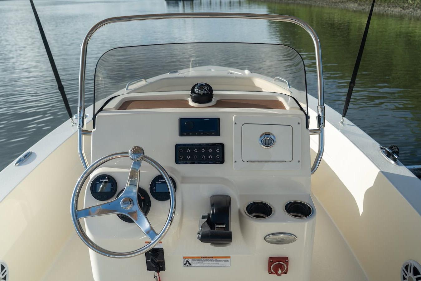 2026 Scout 188 Sportfish boat dashboard with steering wheel and controls on calm water.