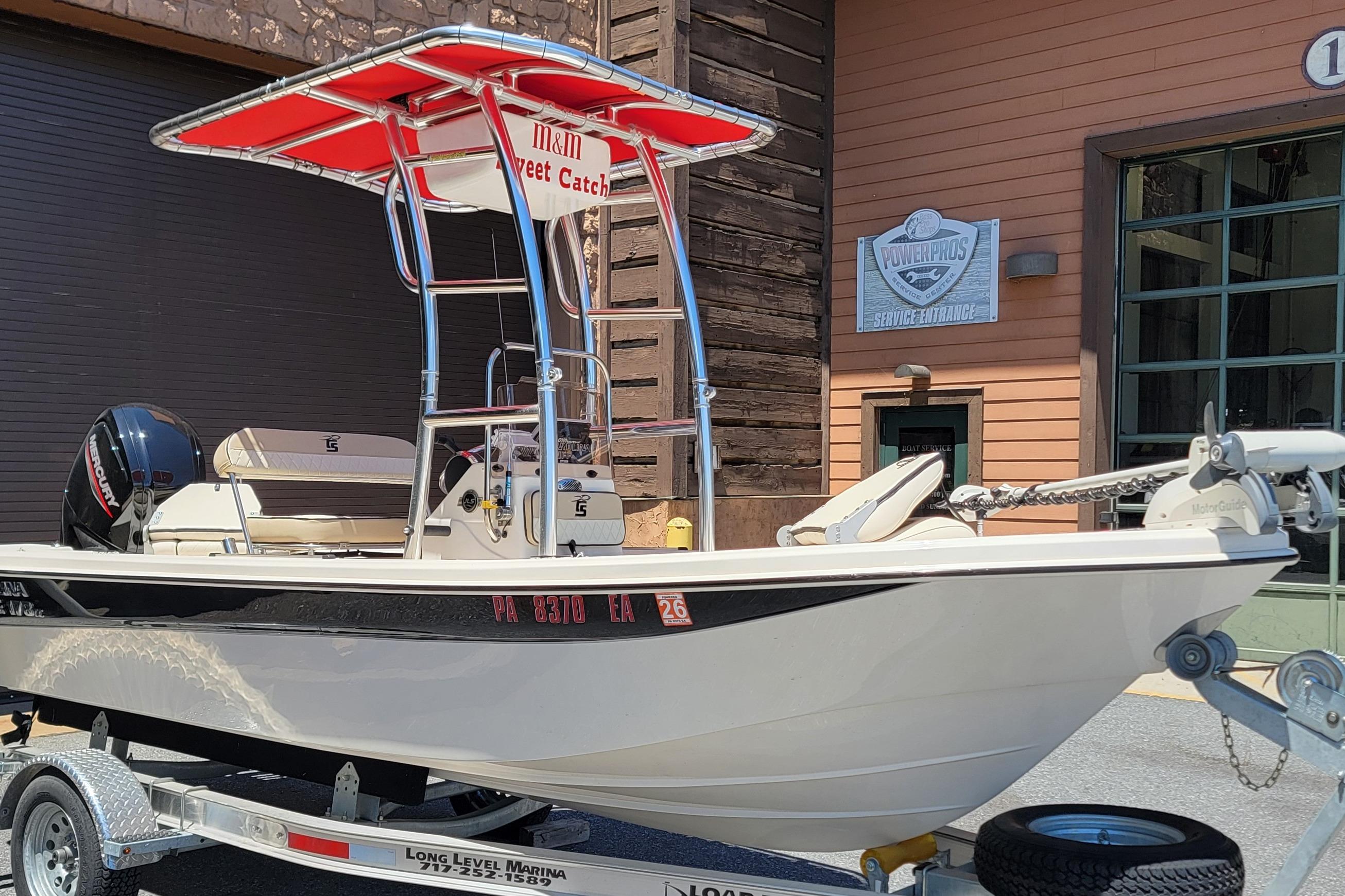 2021 Carolina Skiff 178 JLS boat on trailer, featuring red canopy and Mercury engine.