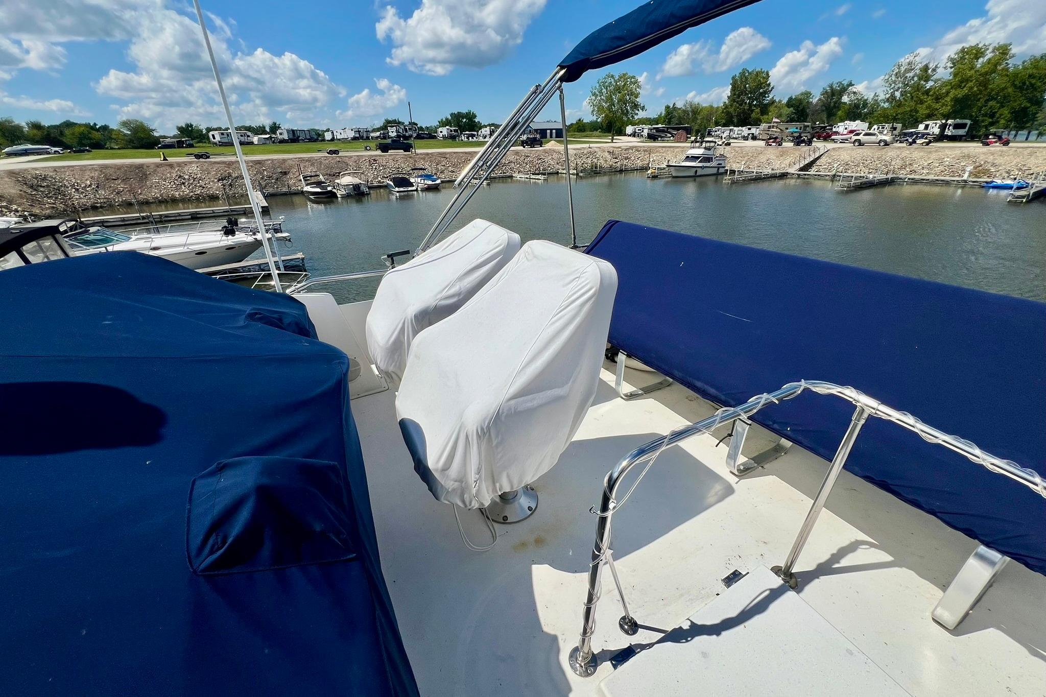 1984 Bertram 42 Flybridge Motor Yacht with covered seats, docked in a marina under blue skies.