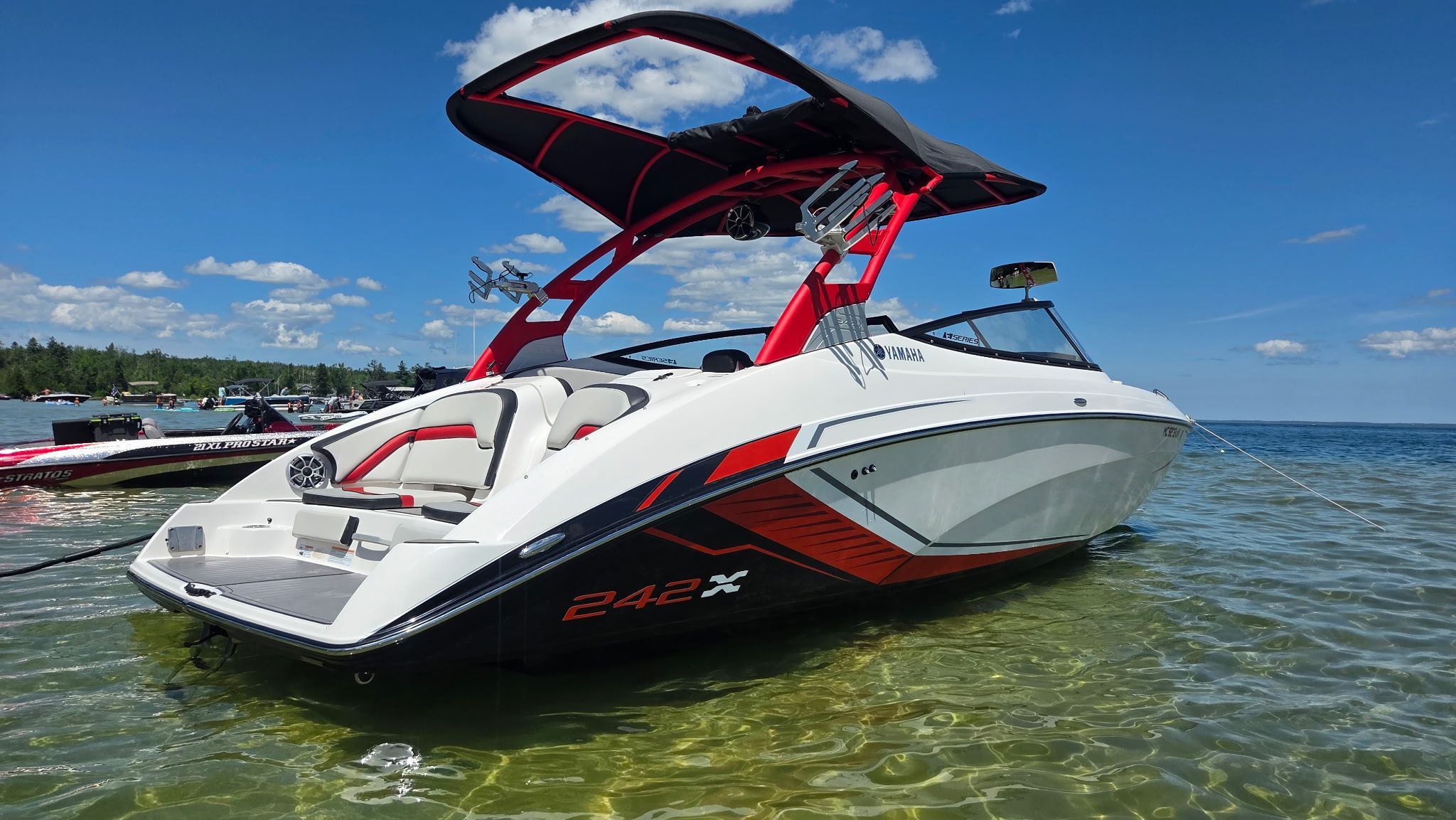 A 2018 Yamaha 242X E-Series boat in clear water, featuring sleek design and red accents.