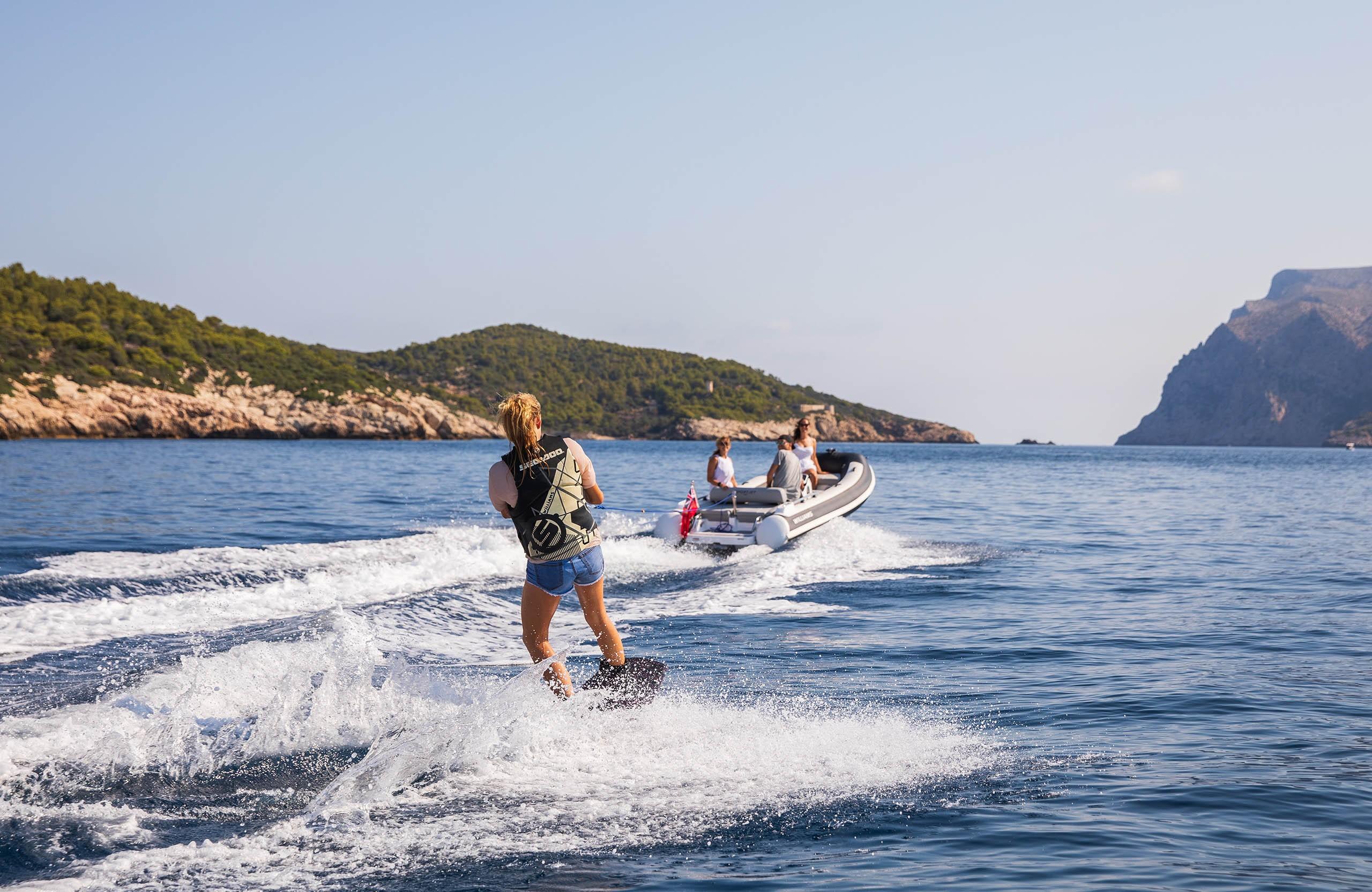 Person wakeboarding behind 2025 Williams Jet Tenders Sportjet 435 in scenic coastal waters.
