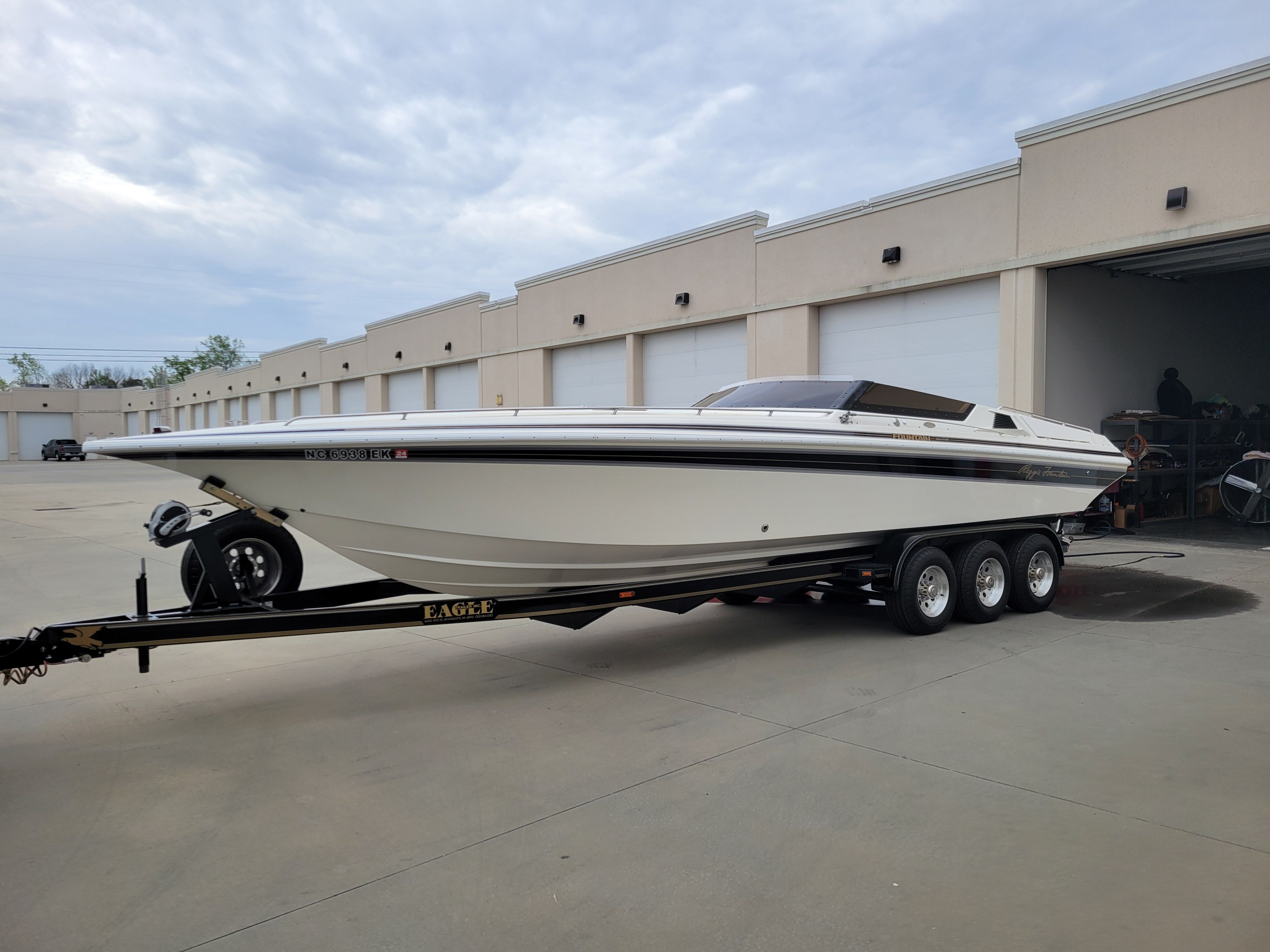 1992 Fountain Fever boat on trailer, parked outside industrial building.