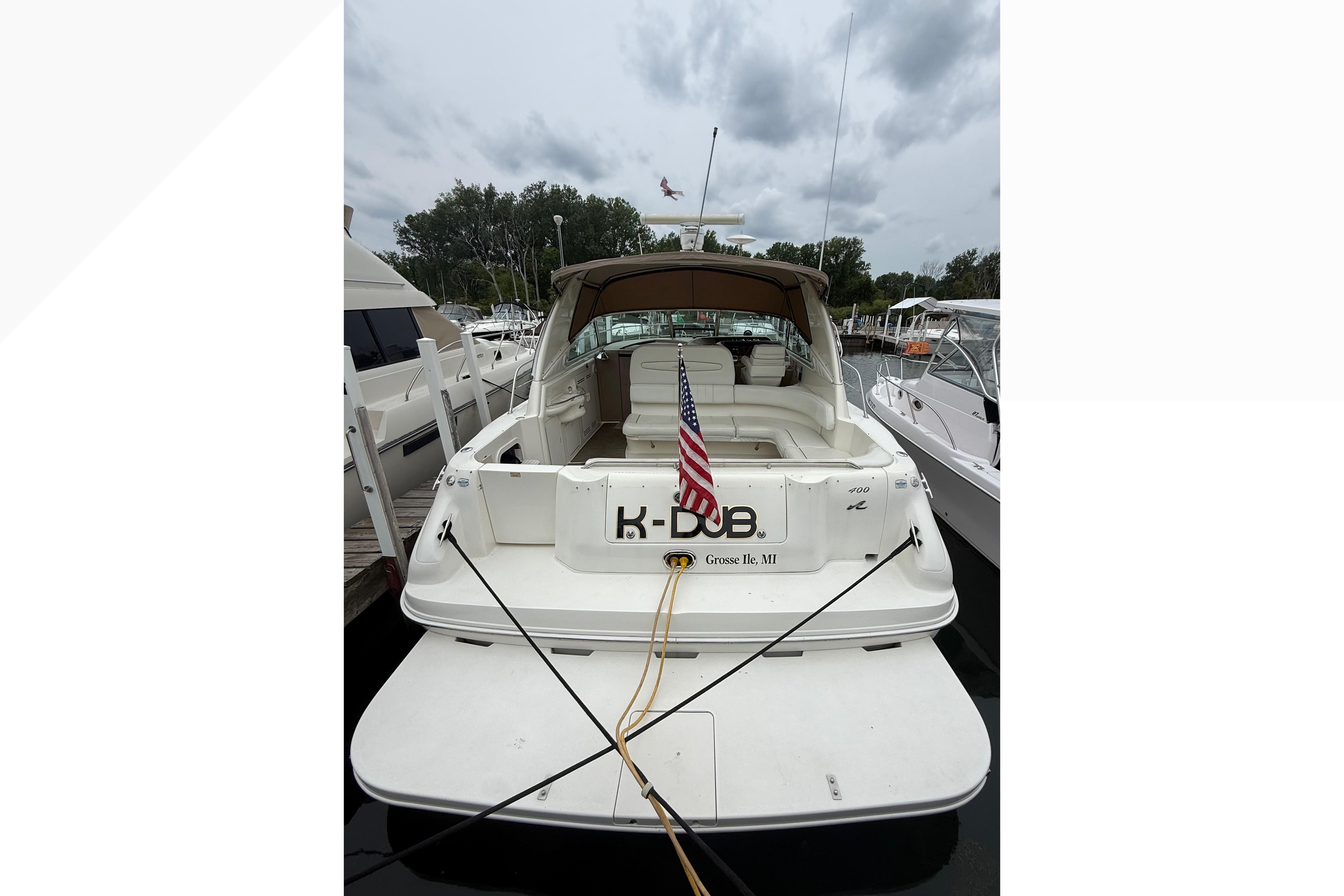 1998 Sea Ray Sundancer 400 docked, rear view with American flag, overcast sky.