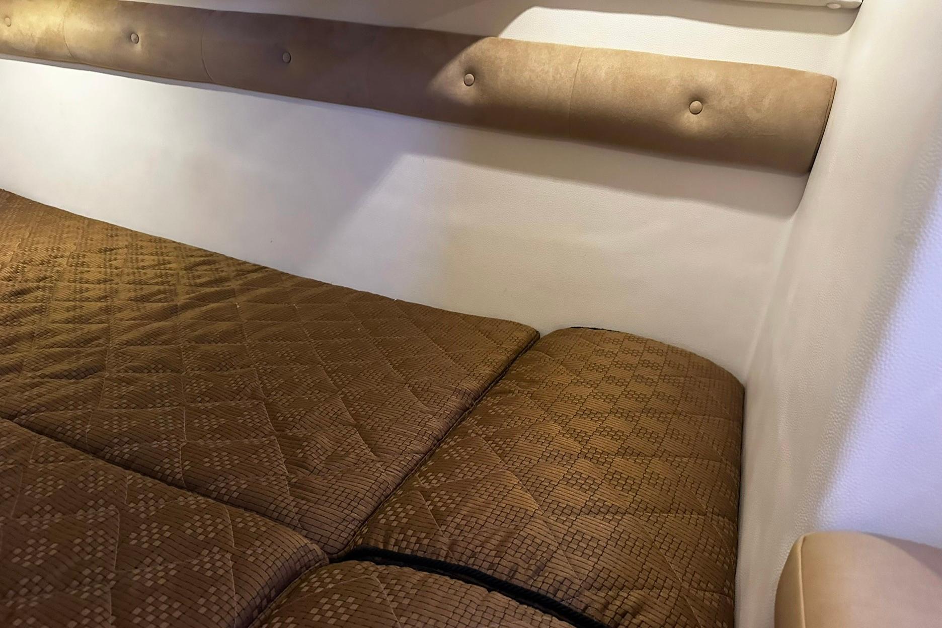 Interior cabin of 2012 Rinker 310 Express Cruiser LE with brown quilted bedding.