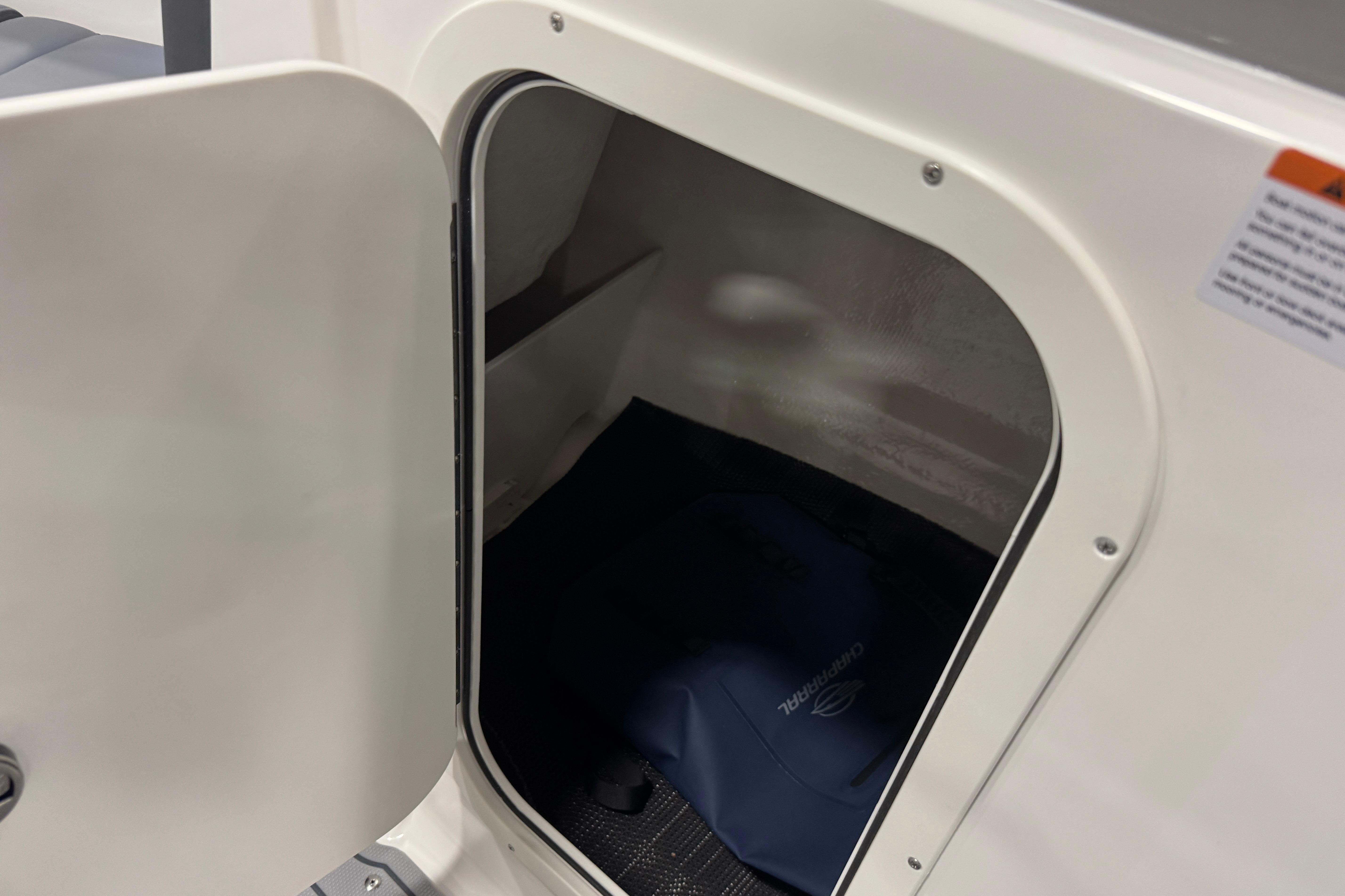 Open storage compartment in 2026 Chaparral 23 SSi boat, showcasing interior space.