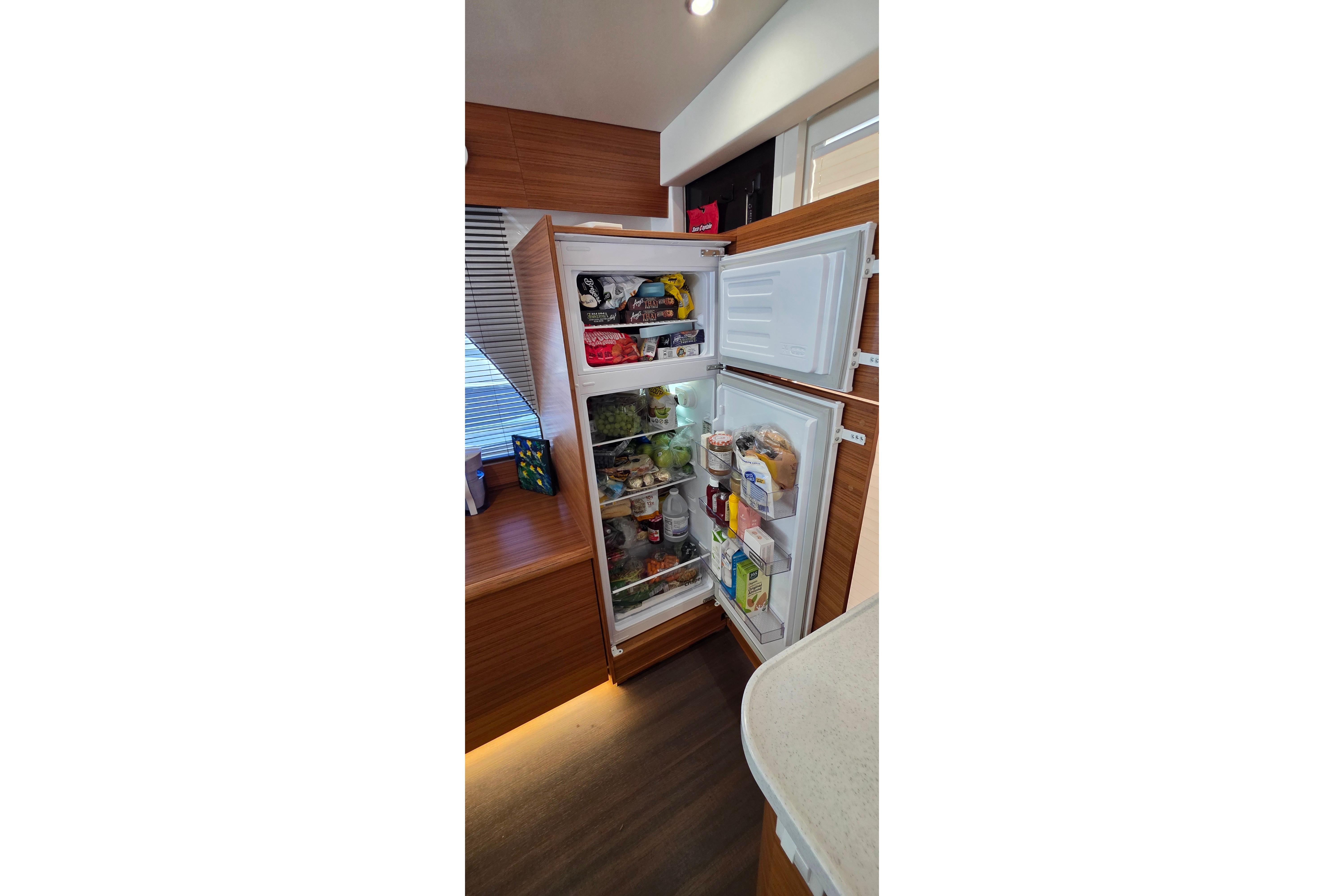 Open refrigerator in 2023 Greenline 40 yacht, stocked with various food items.