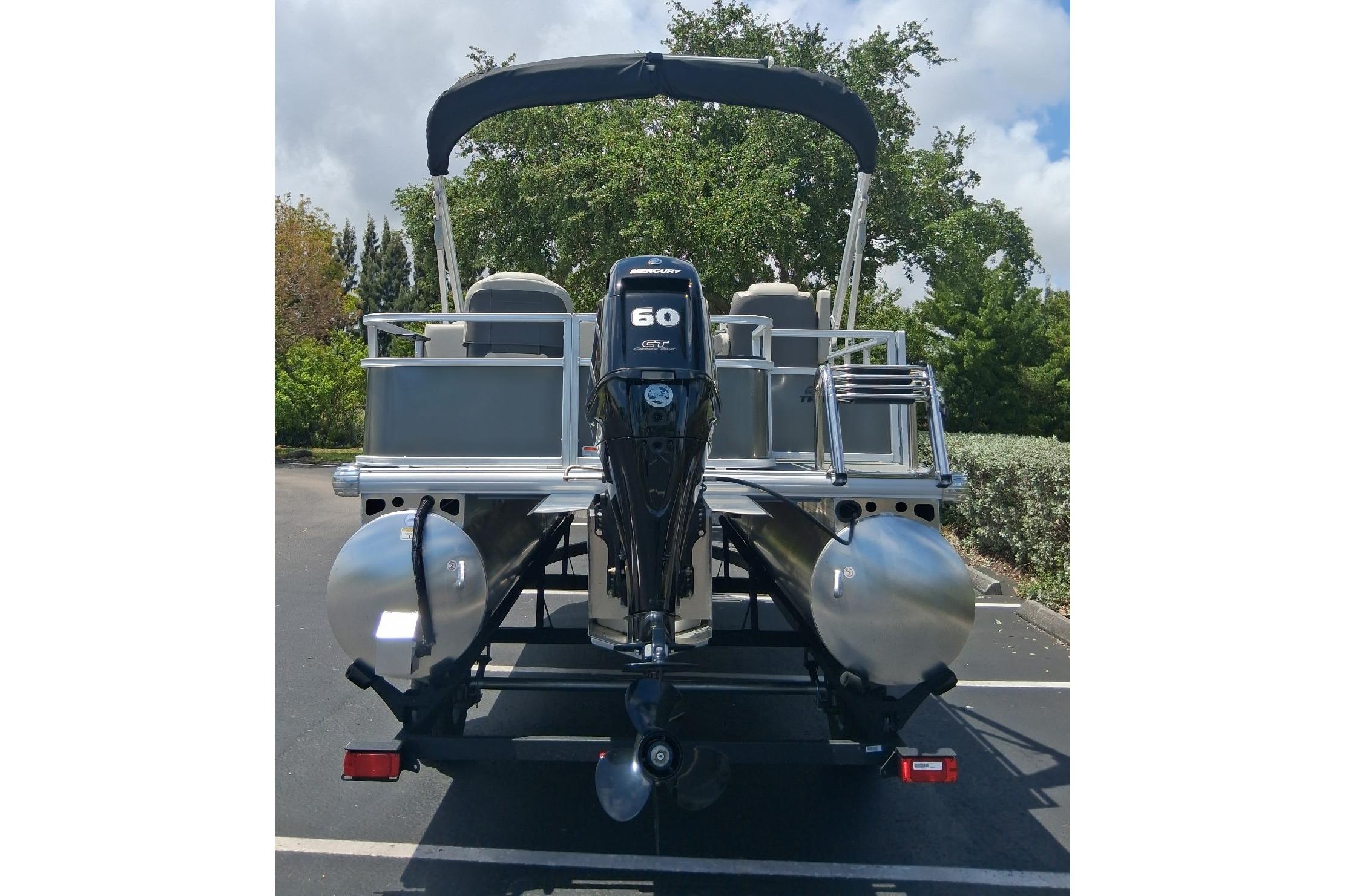 2026 Sun Tracker Bass Buggy 18 DLX pontoon boat with 60 HP engine, parked outdoors.