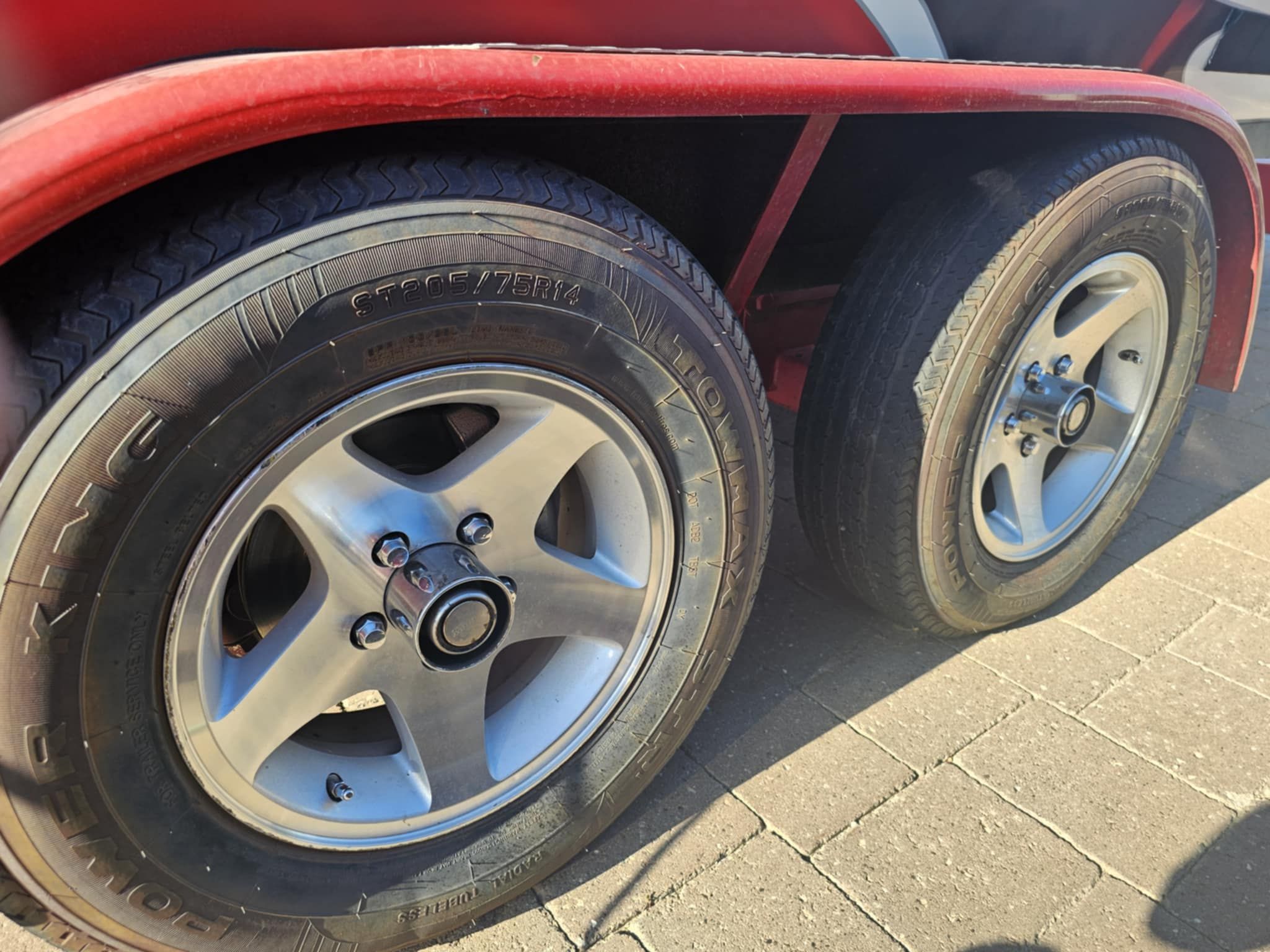 Close-up of MB PIGPR 2006 trailer wheels on pavement.