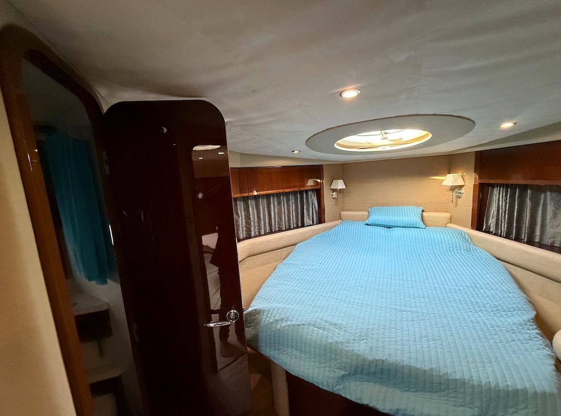 Luxurious 2009 Princess V53 yacht bedroom with blue bedding and elegant lighting.