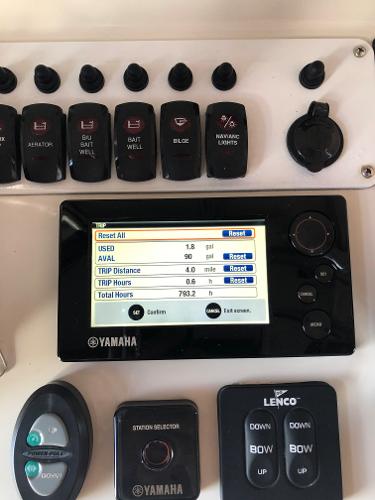 Yamaha control panel with various switches and a digital display on a boat.