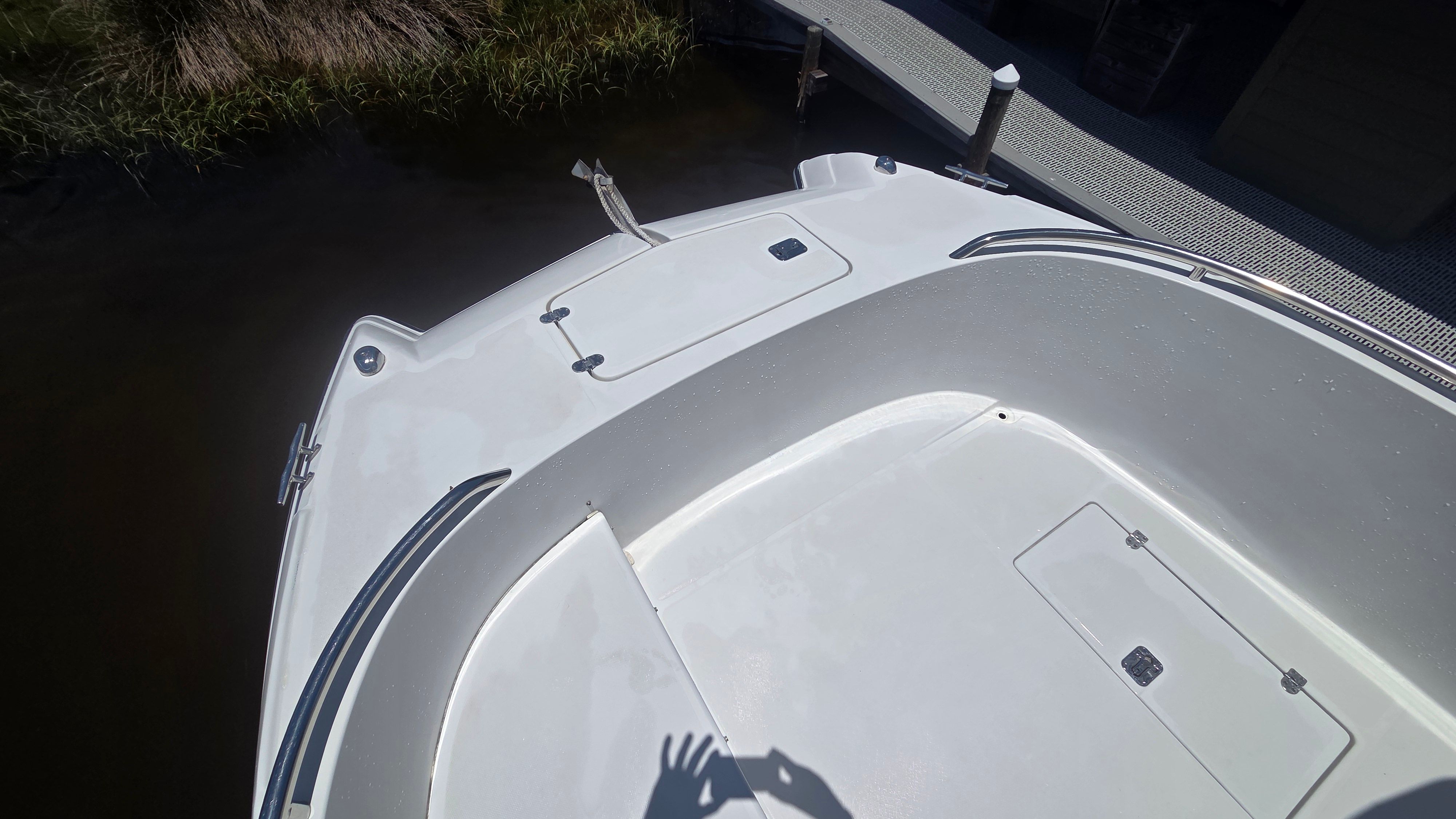 The boat features a spacious foredeck with storage hatches and a railing.