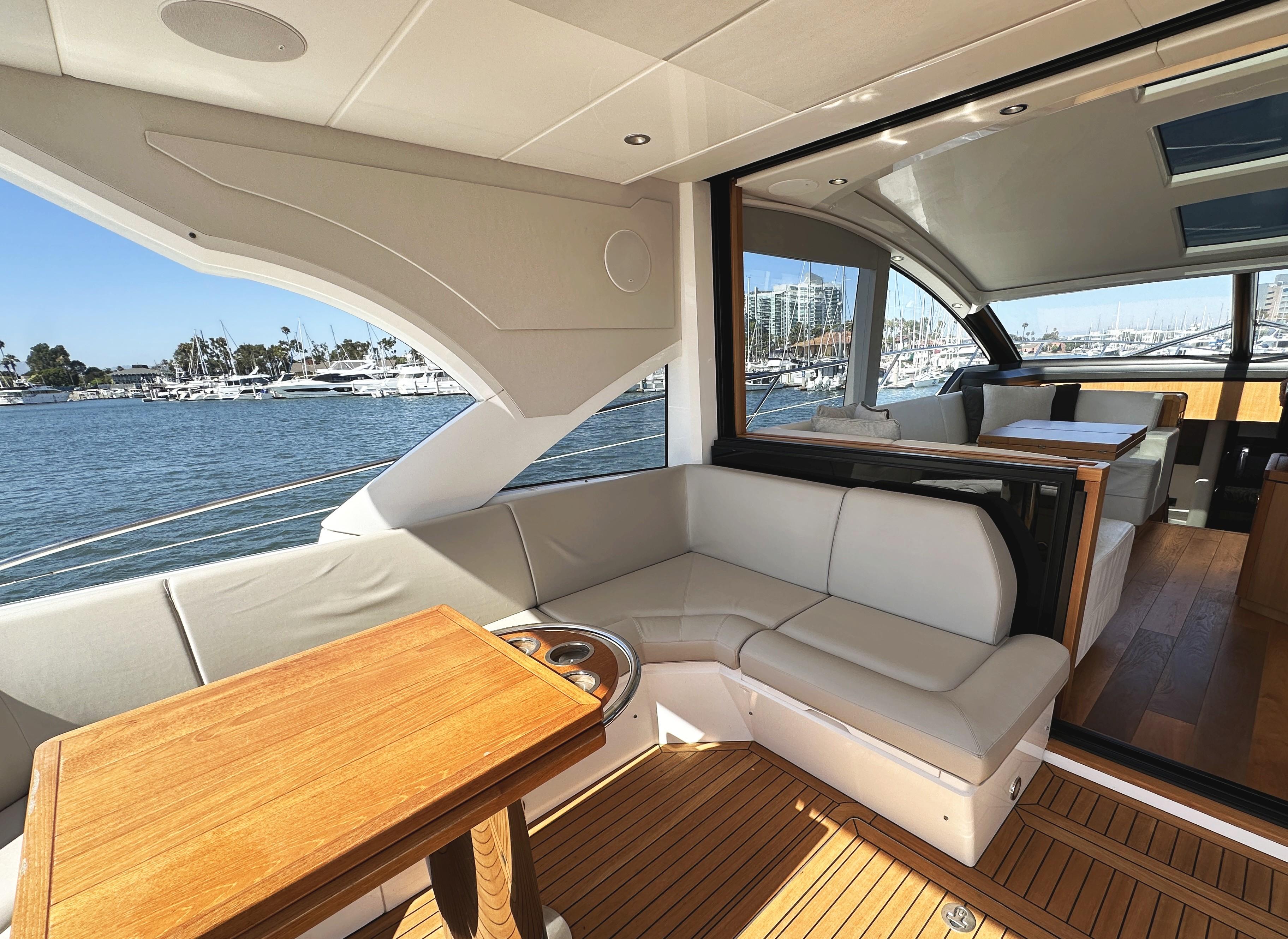 Luxurious 2019 Sunseeker Predator 57 yacht interior with elegant seating and scenic marina view.