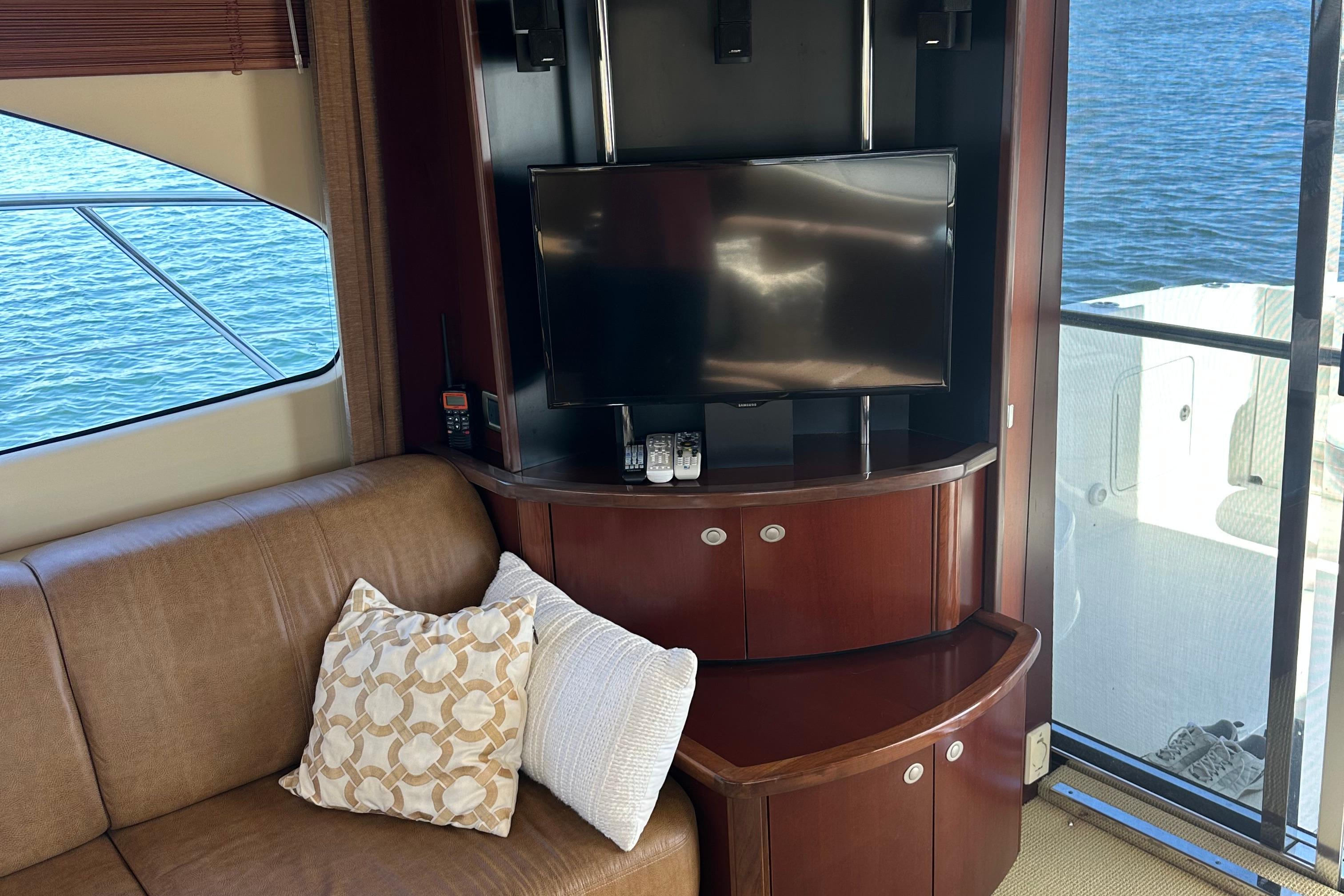 Luxurious 2005 Sea Ray 500 Sedan Bridge interior with TV, sofa, and water view.