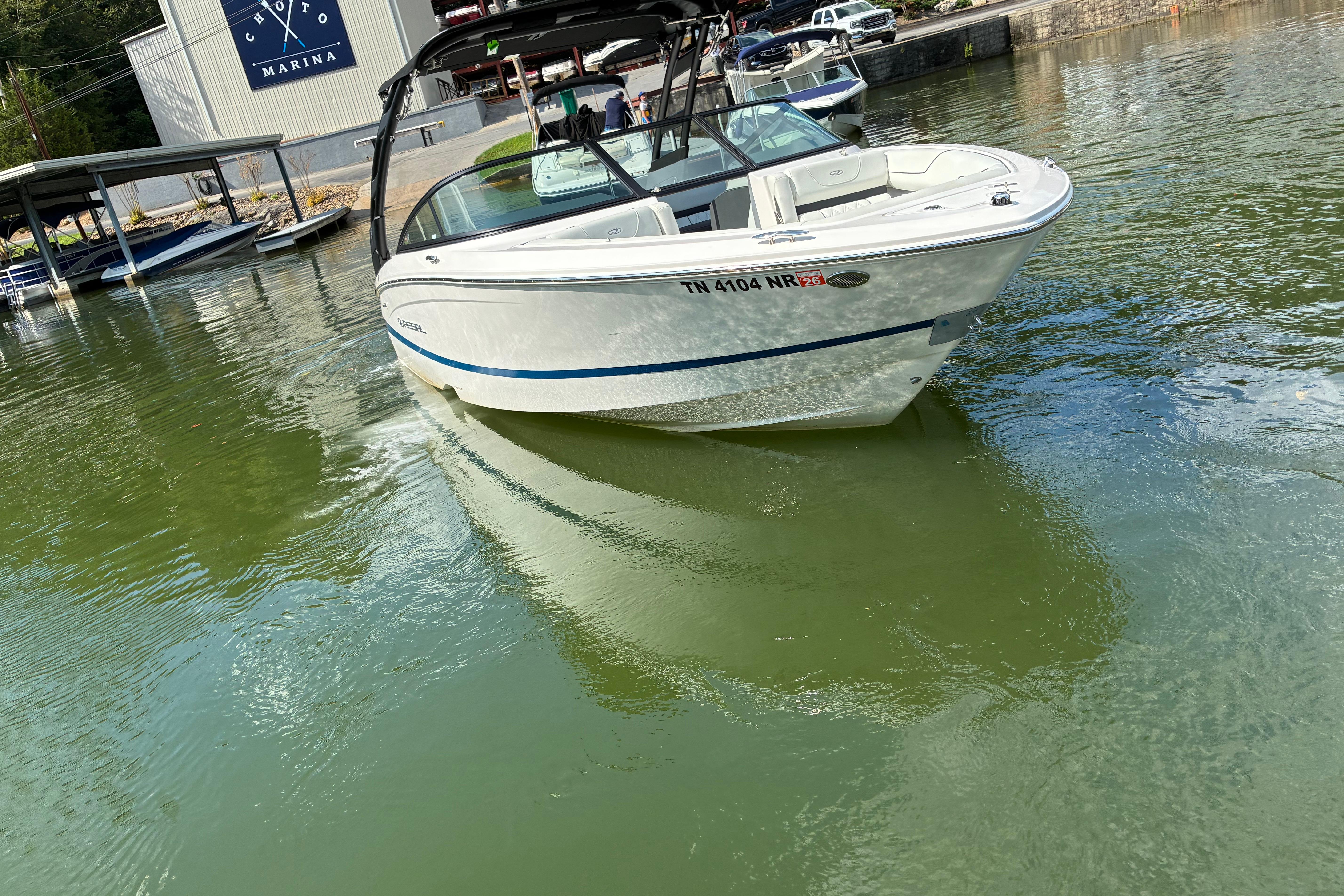2025 Regal LS2 boat cruising near marina, reflecting on calm water.