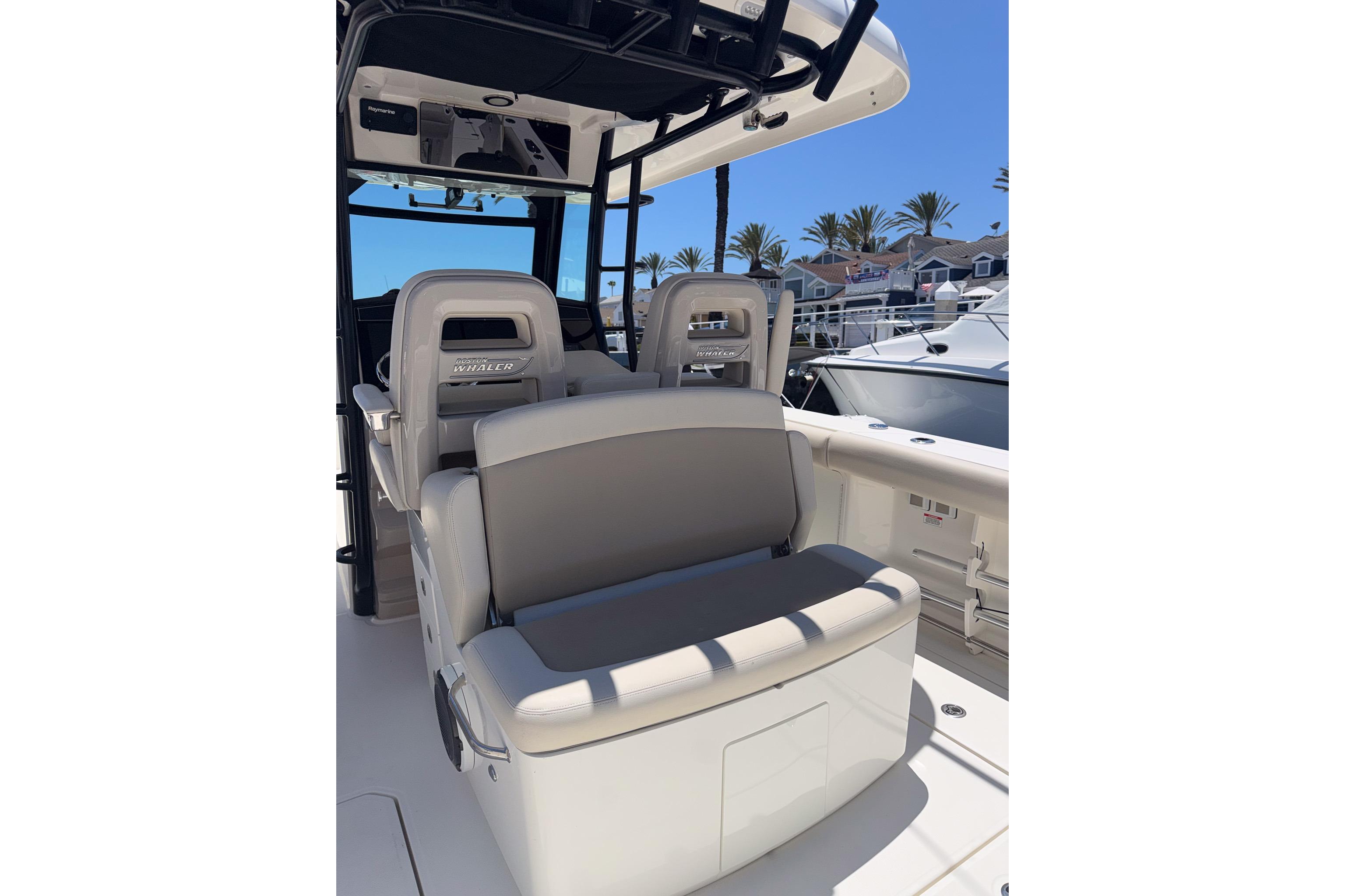 2021 Boston Whaler 330 Outrage boat interior with seating and helm, docked under clear blue sky.
