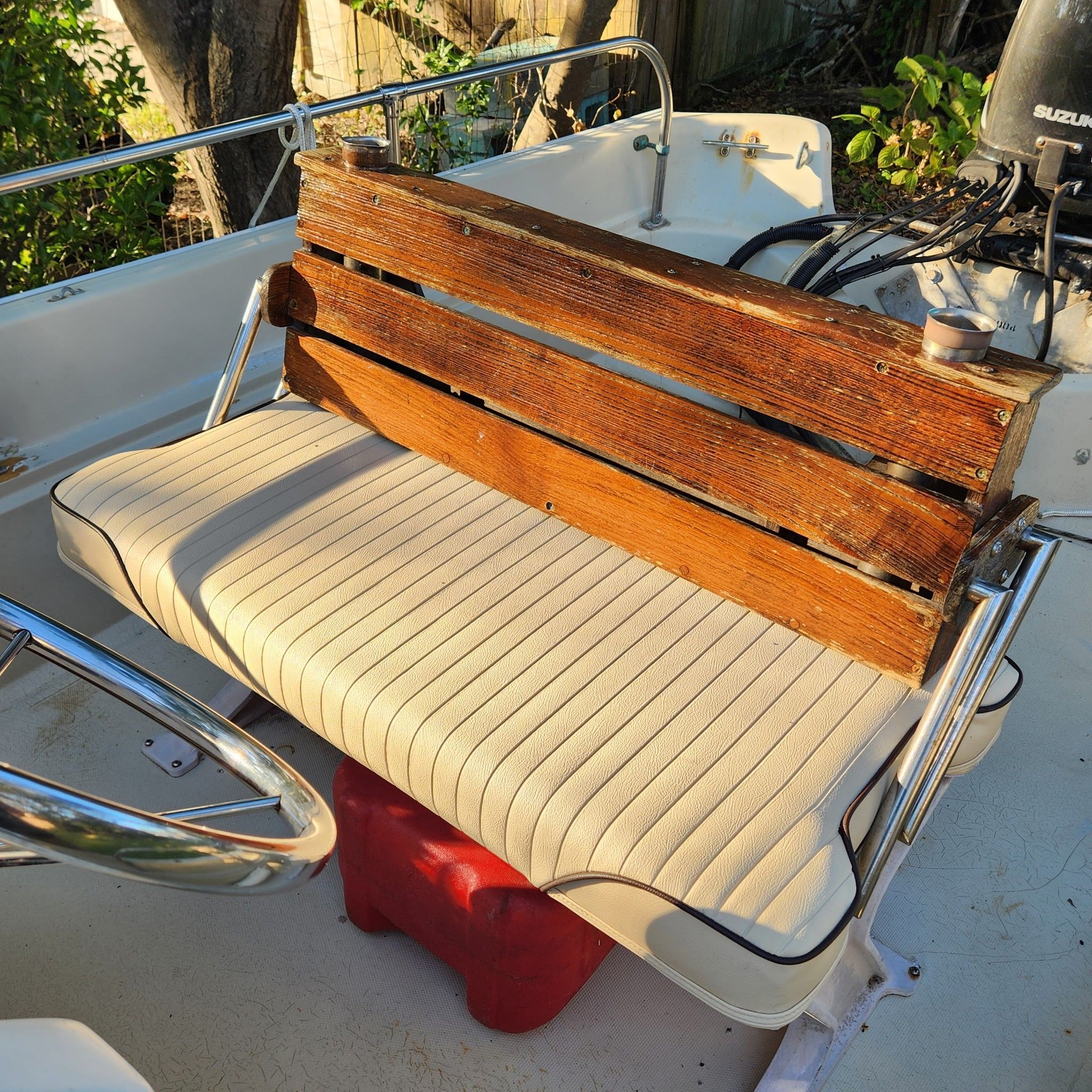 A wooden bench seat on a 1976 Boston Whaler MONTAUK, with padded seating and metal railing.