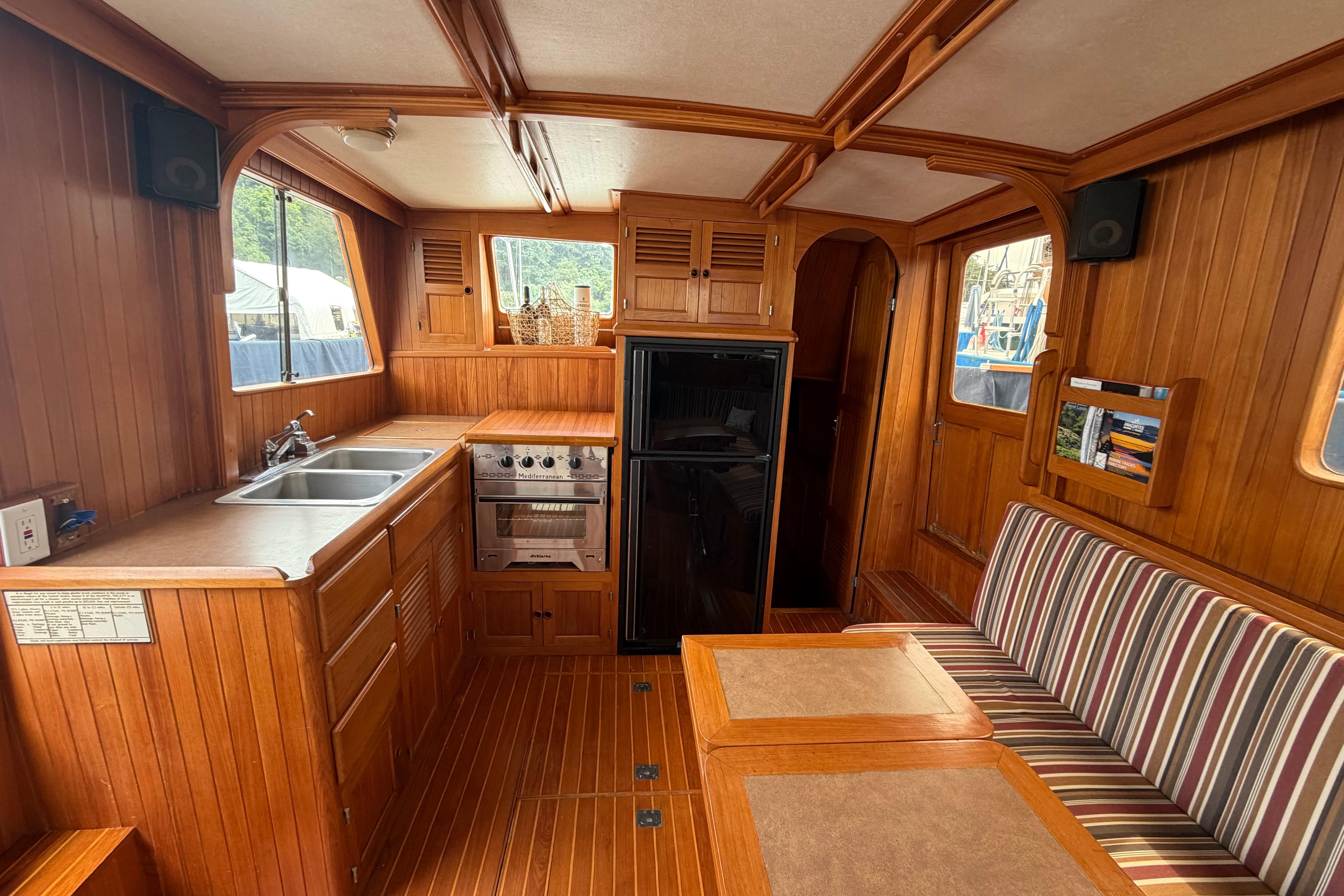 Interior of a 1988 Monk 36 boat with wooden cabinetry and striped seating.