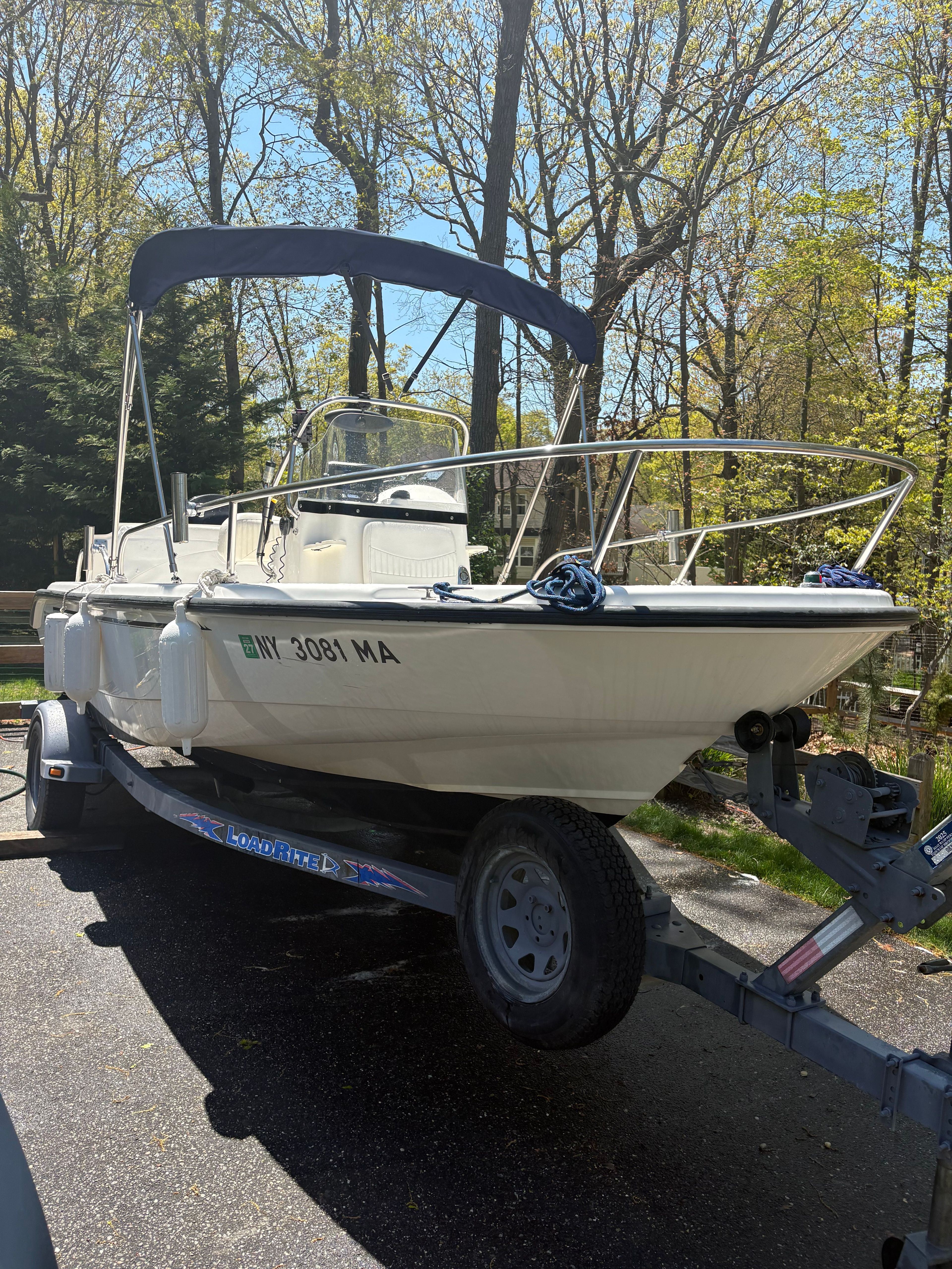 Boston Whaler 180 Dauntless 2004 on trailer parked in wooded area.