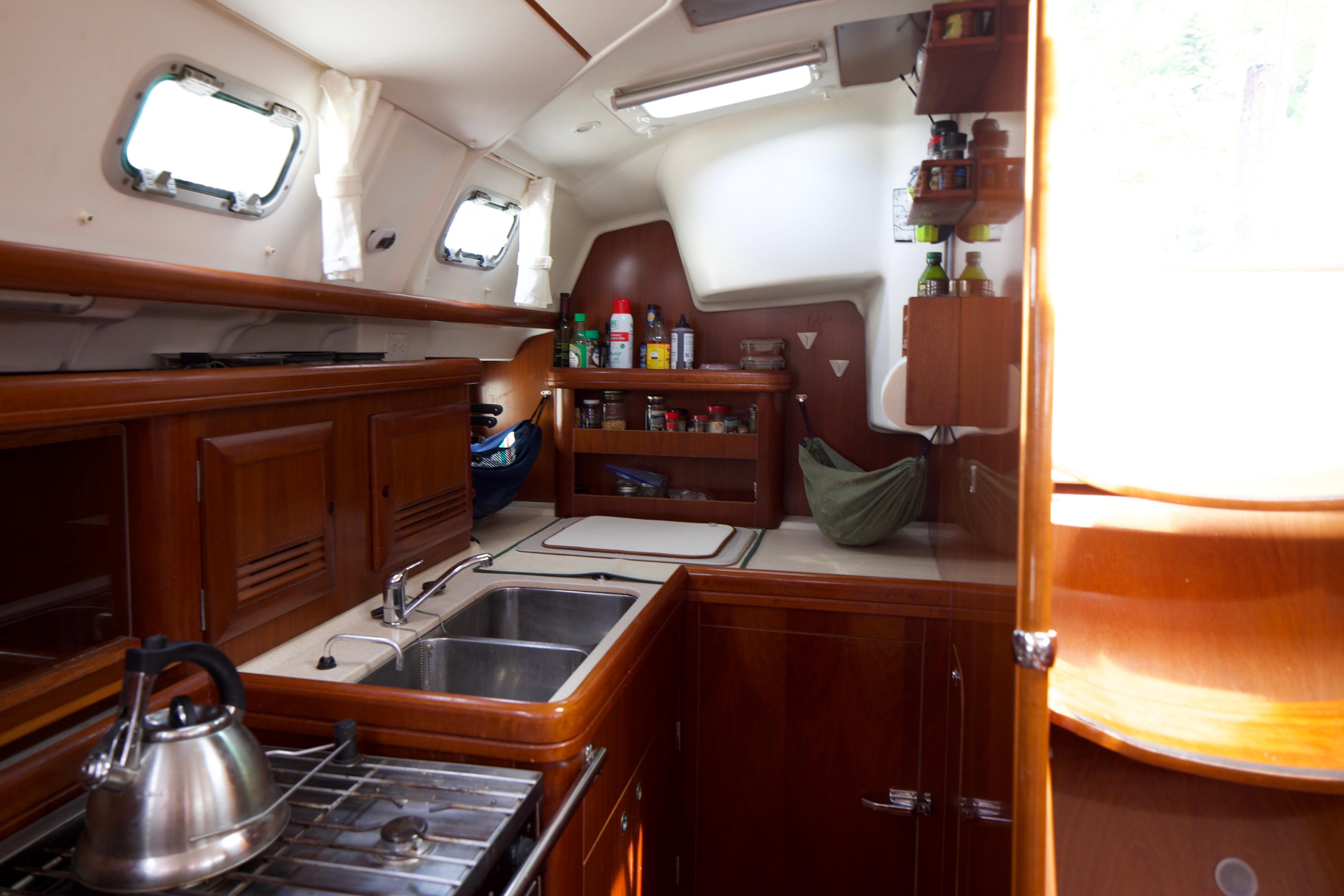 Interior of 2005 Beneteau 423 sailboat kitchen with wooden cabinetry and stainless steel sink.