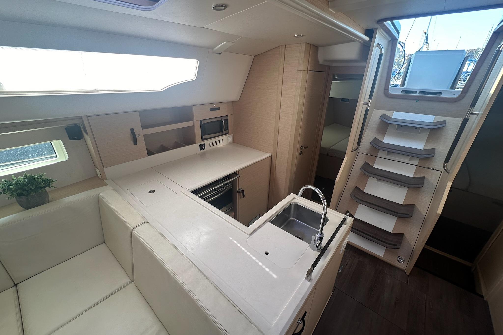 Luxurious interior of 2018 Jeanneau 51 yacht featuring modern kitchen and elegant staircase.