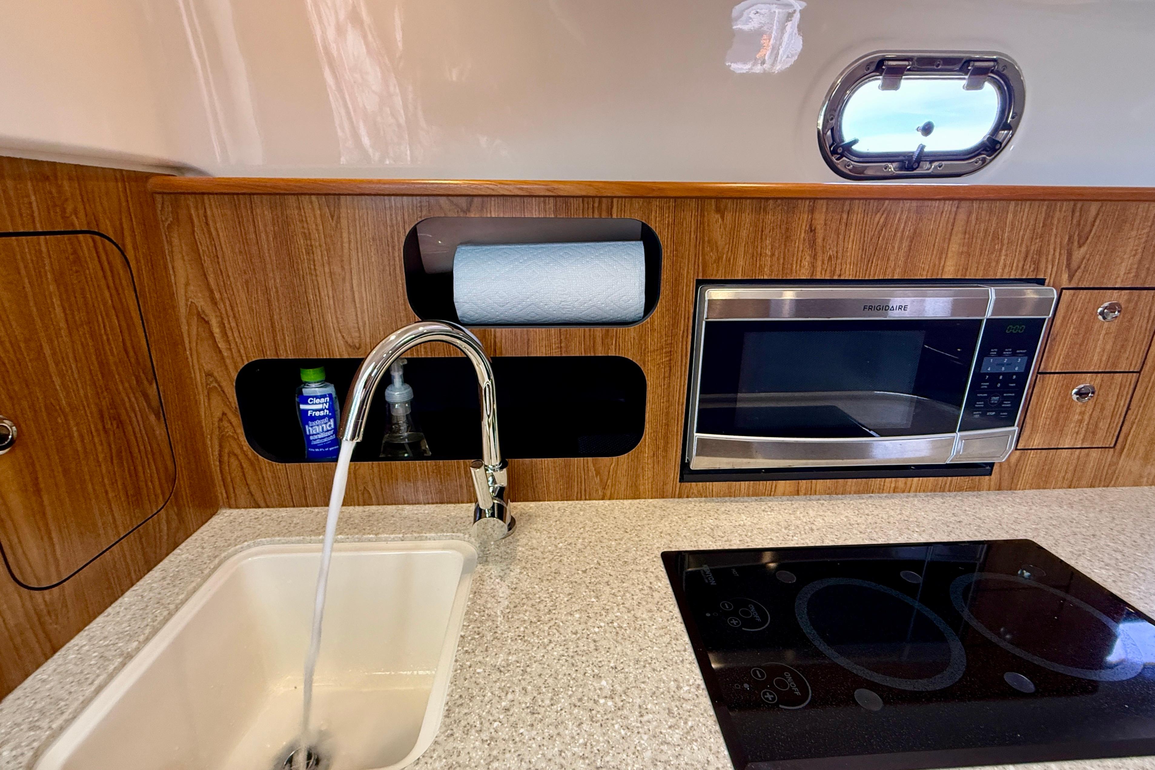 2012 Pursuit OS 345 Offshore kitchen with sink, microwave, and stovetop.