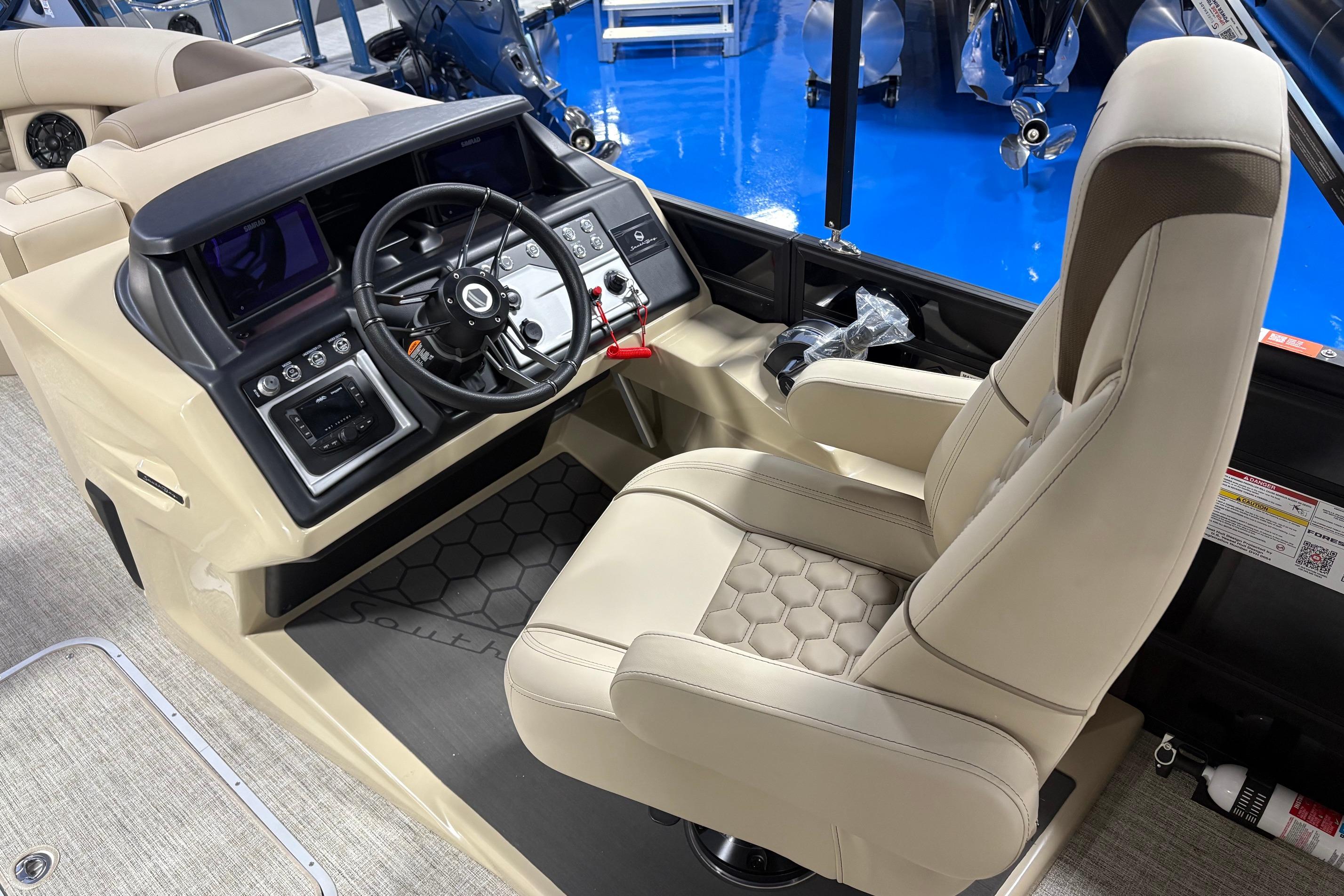Captain's seat and helm of 2026 South Bay 523RS boat, featuring modern controls and beige upholstery.