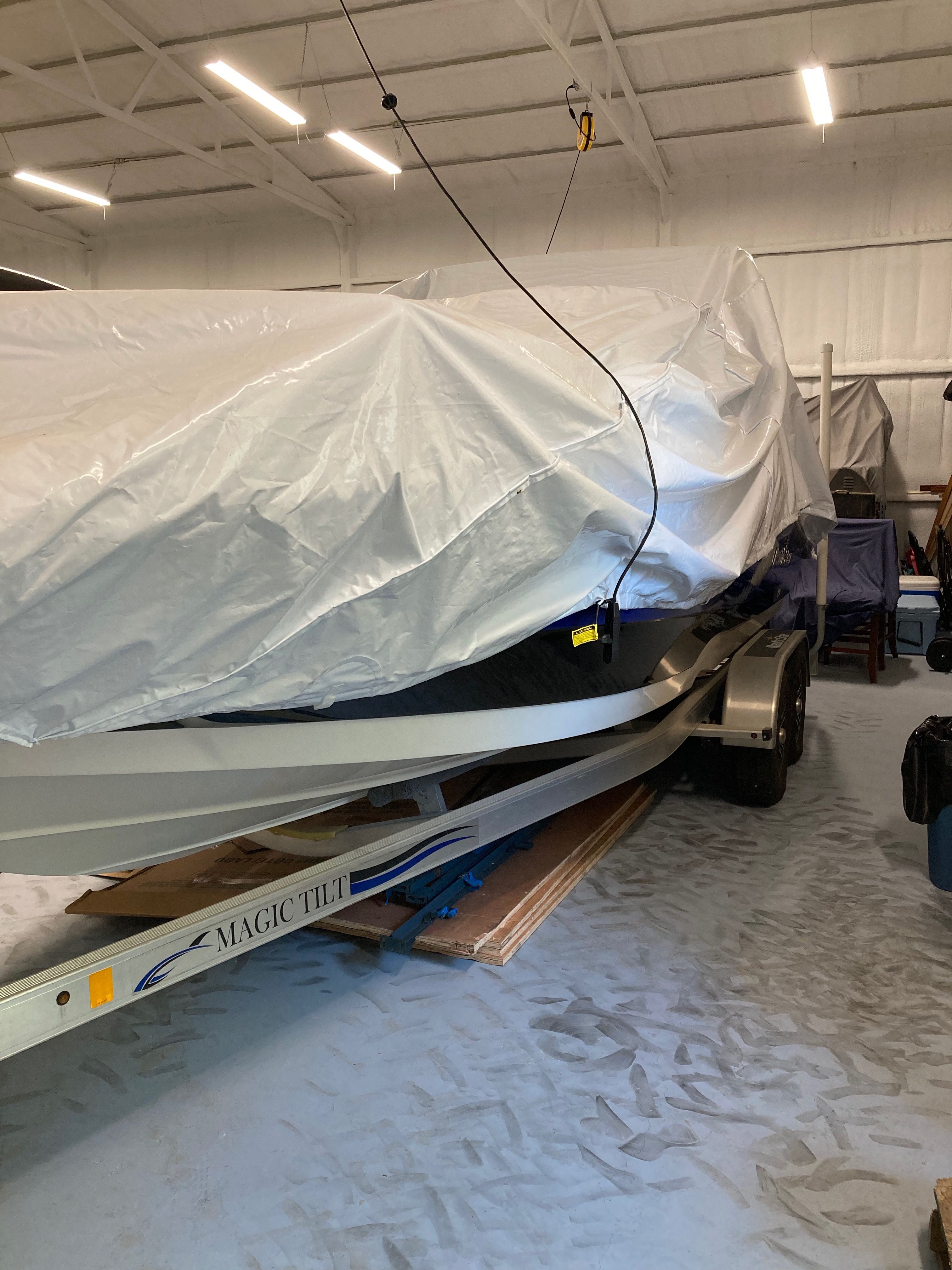 A 2016 Custom 223 DC boat, covered and on a trailer in a warehouse.