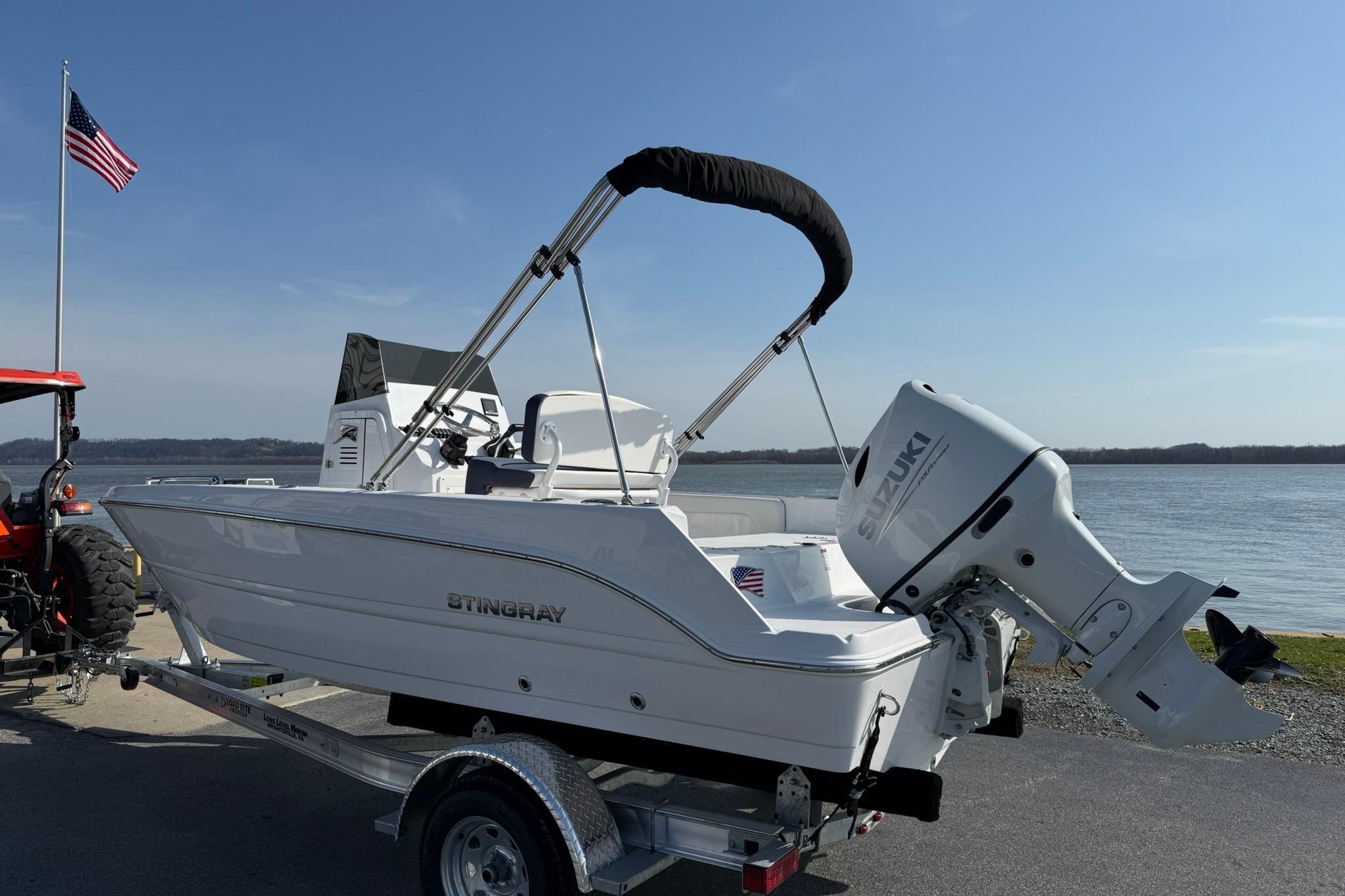 2026 Stingray 173 CC boat with Suzuki engine on trailer by a lake.