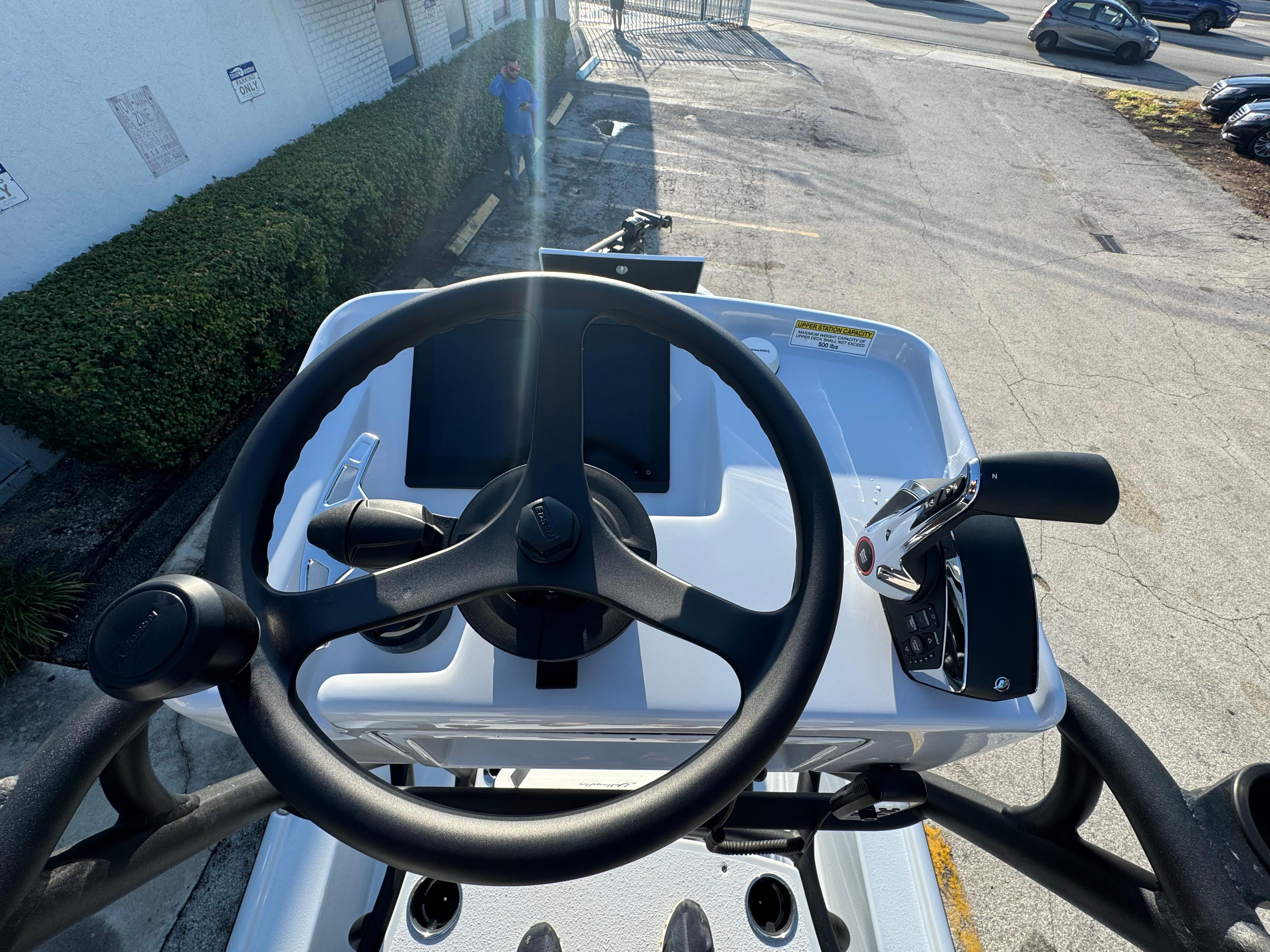 2025 Yellowfin 24 CE boat helm with steering wheel and controls, parked outdoors.