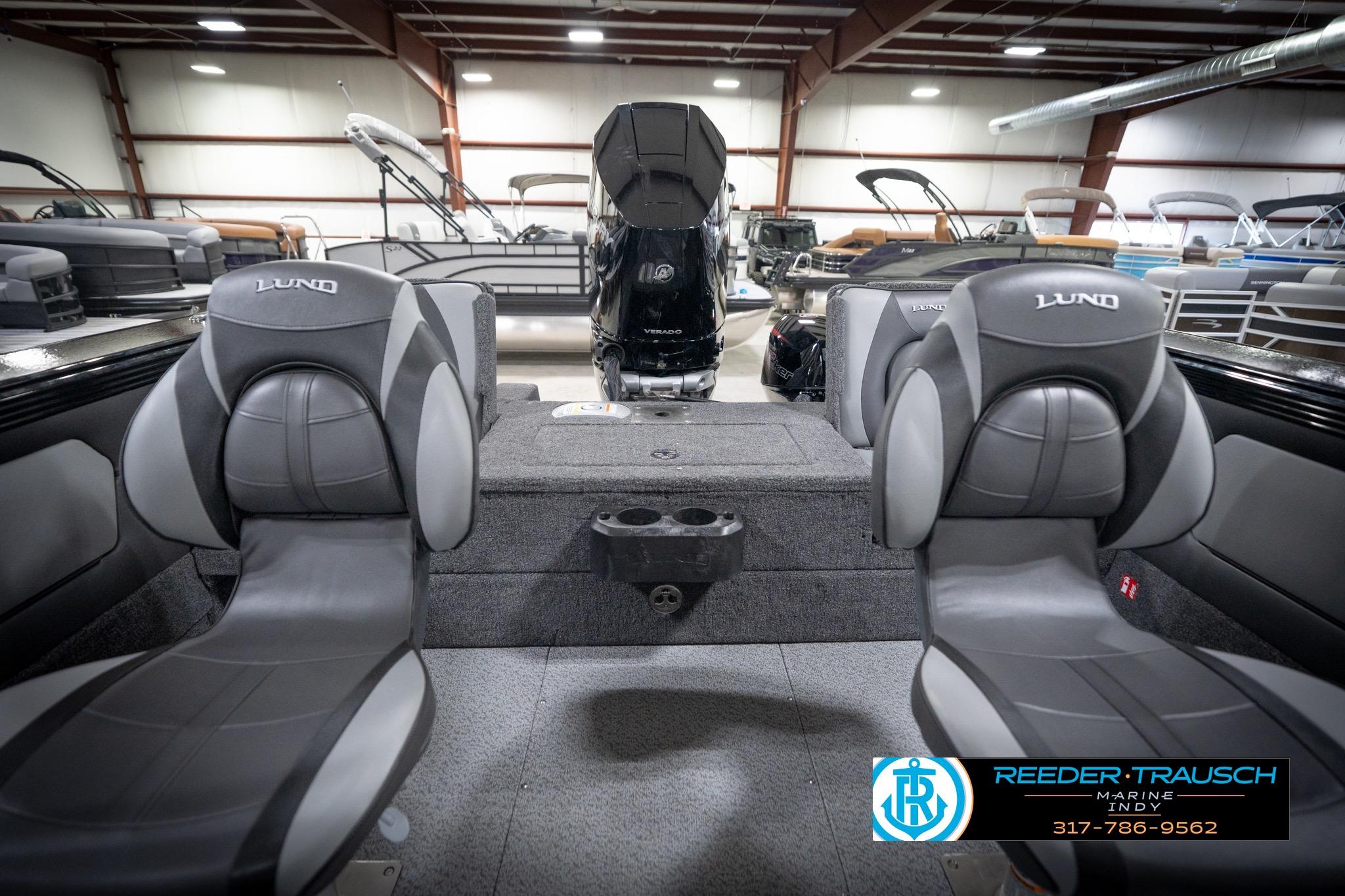 2026 Lund 2275 Baron boat interior with seating and motor, displayed in a showroom.