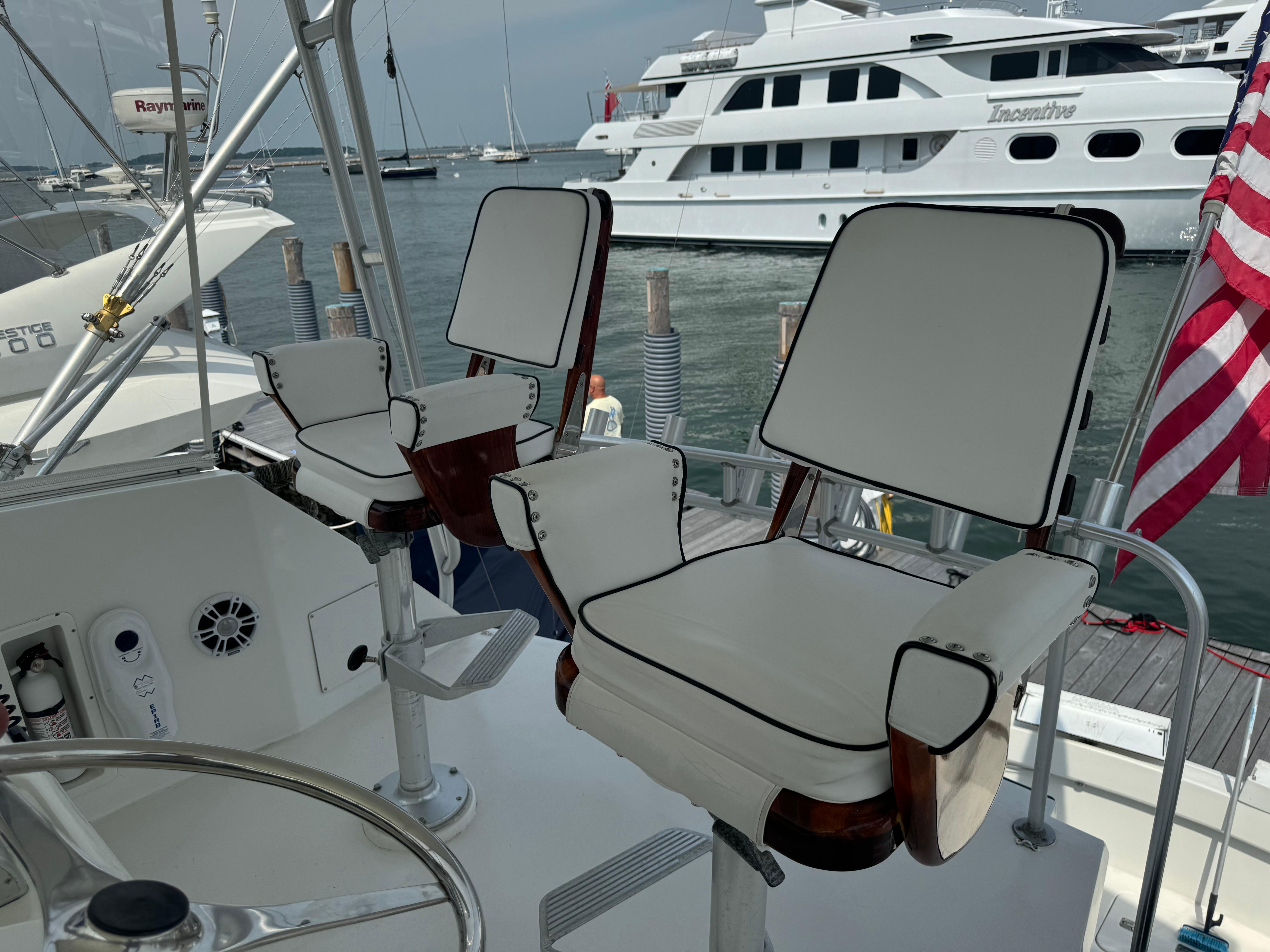 1994 Hatteras 54 Convertible yacht helm with white cushioned chairs, docked near other boats.