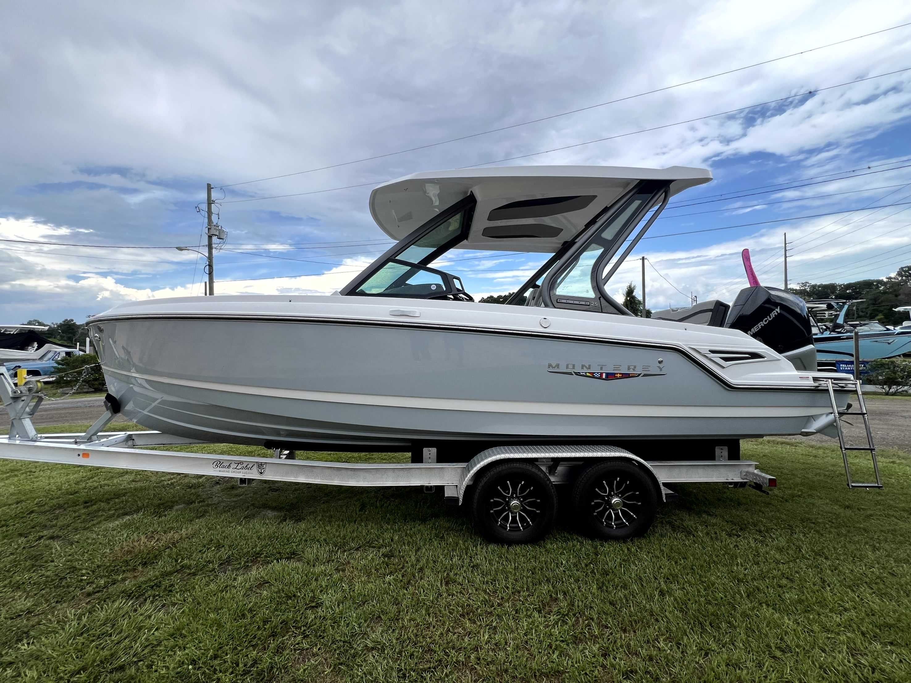 A 2026 Monterey Elite 25 boat on a trailer, set on grass.