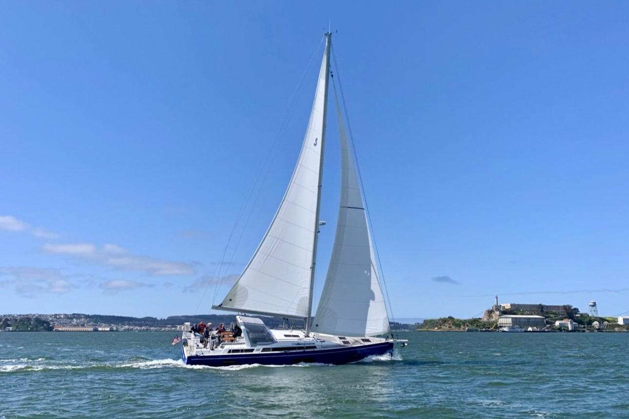 2022 Beneteau Oceanis Yacht 54 sailing on open water under clear blue skies.