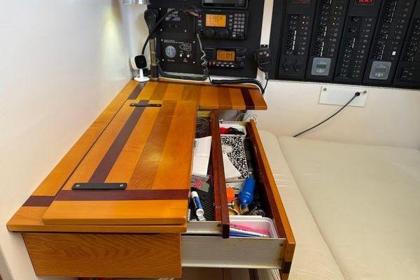 Wooden desk with open drawer, nautical equipment, and control panels on a Reliance 44, 2011 model.