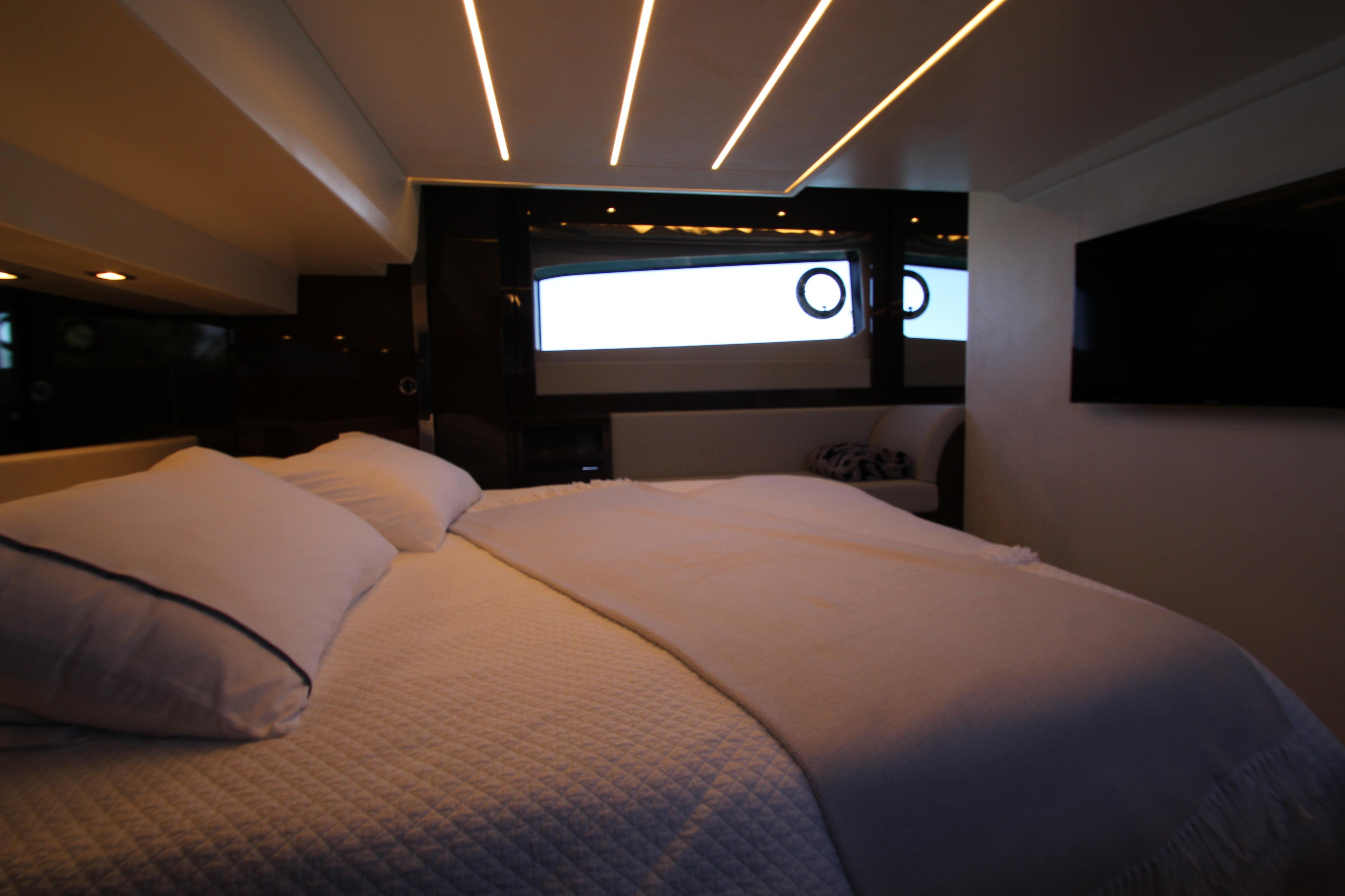 Luxurious bedroom interior of 2022 Prestige 520 yacht with modern lighting and elegant bedding.