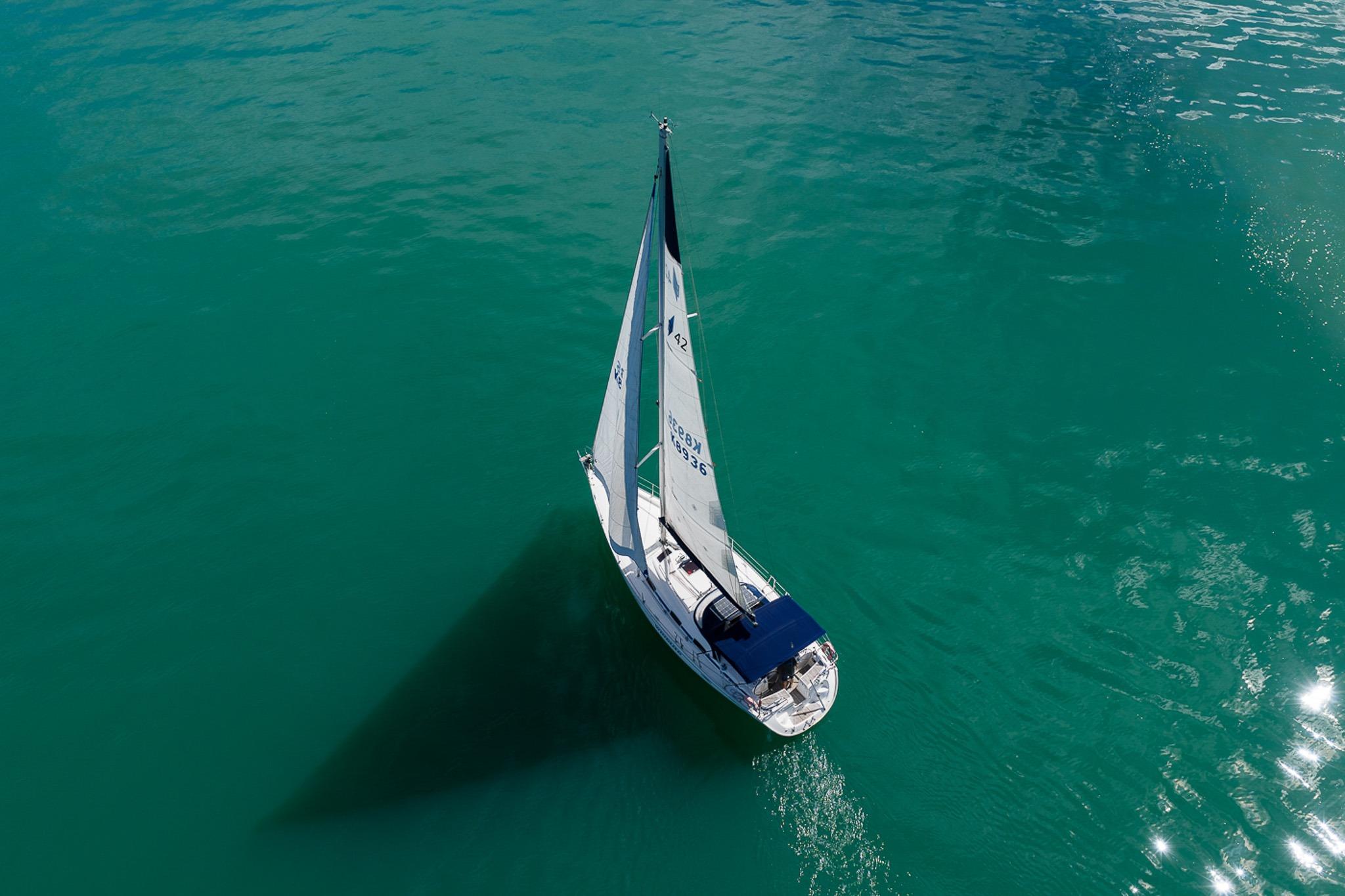Aerial view of 2005 Bavaria Cruiser 42 sailboat on turquoise water.