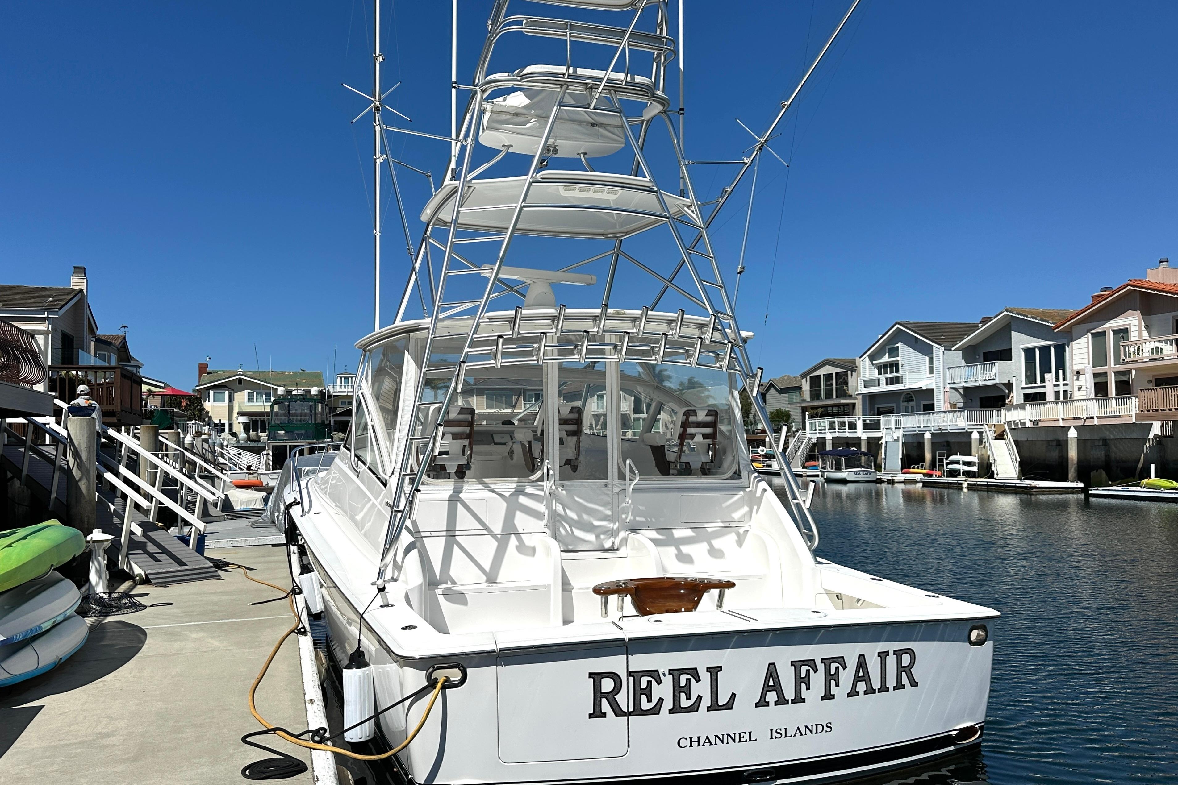 2012 Viking 42 Open yacht docked at marina, clear blue sky, waterfront homes.