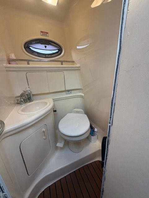 The image shows a boat bathroom with a sink, toilet, and porthole.