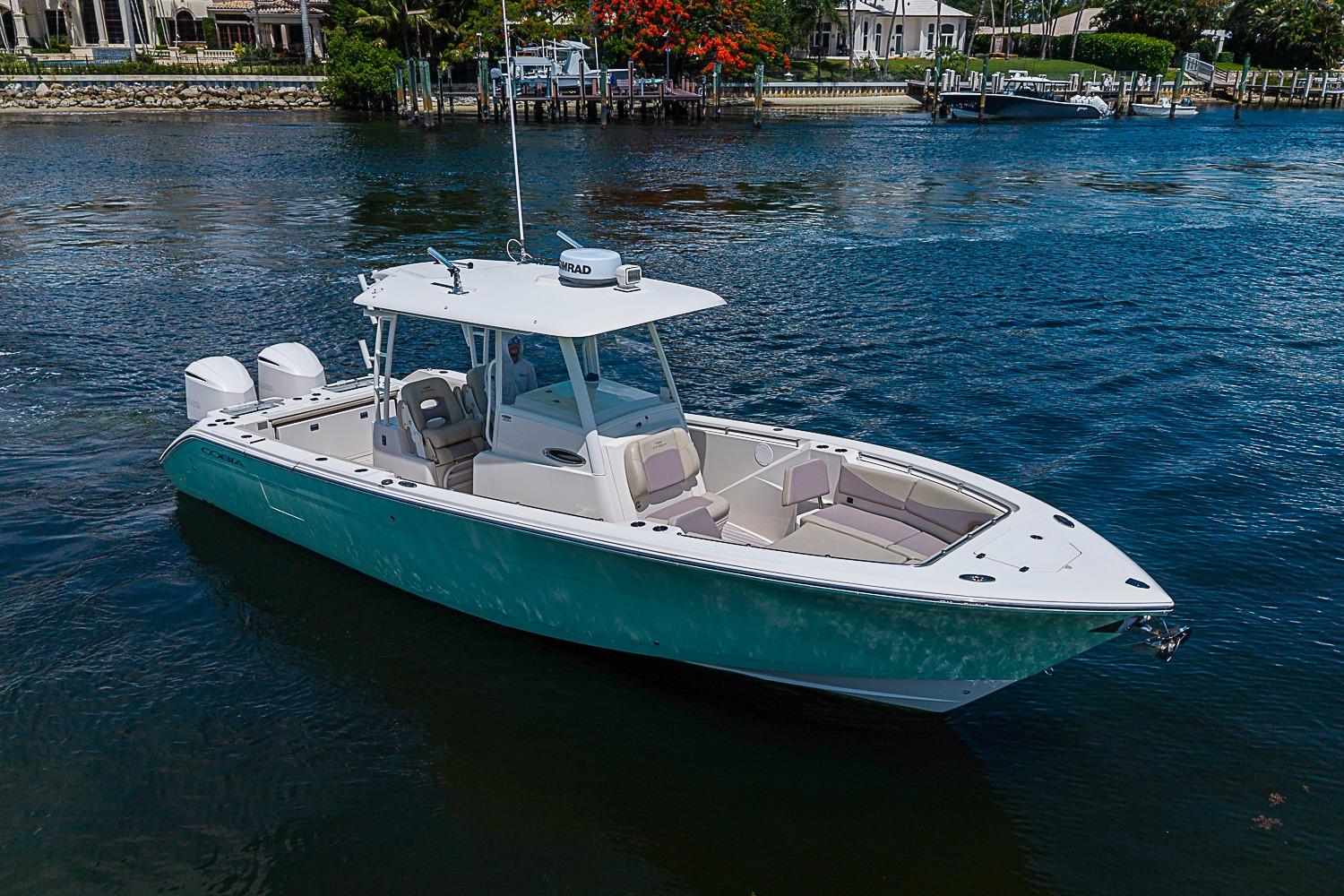 2019 Cobia 320 Center Console boat on calm water, featuring dual engines and spacious seating.