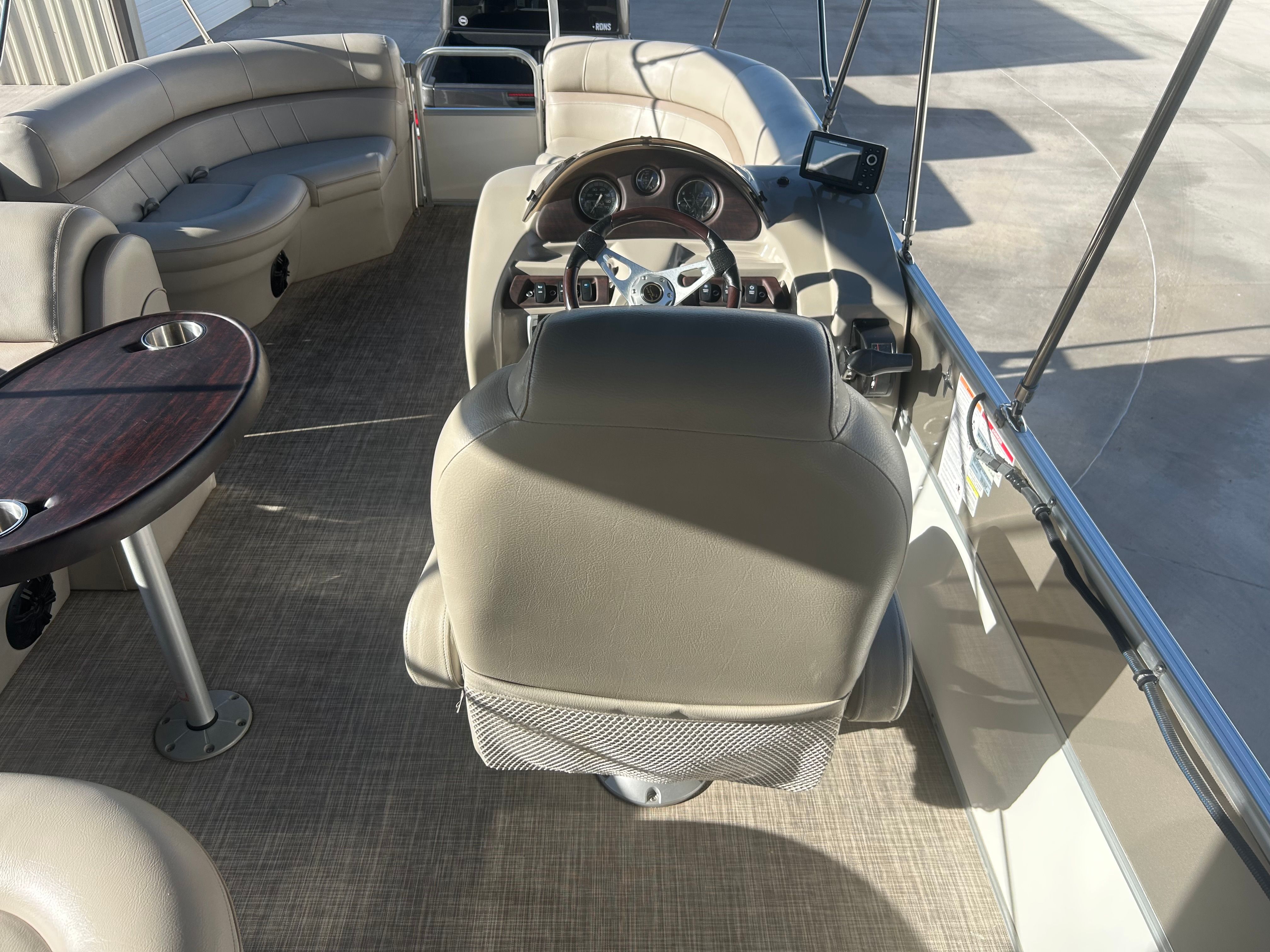 The image shows the cockpit of a 2018 Berkshire 24RFX CTS pontoon boat with beige seating and a steering wheel.