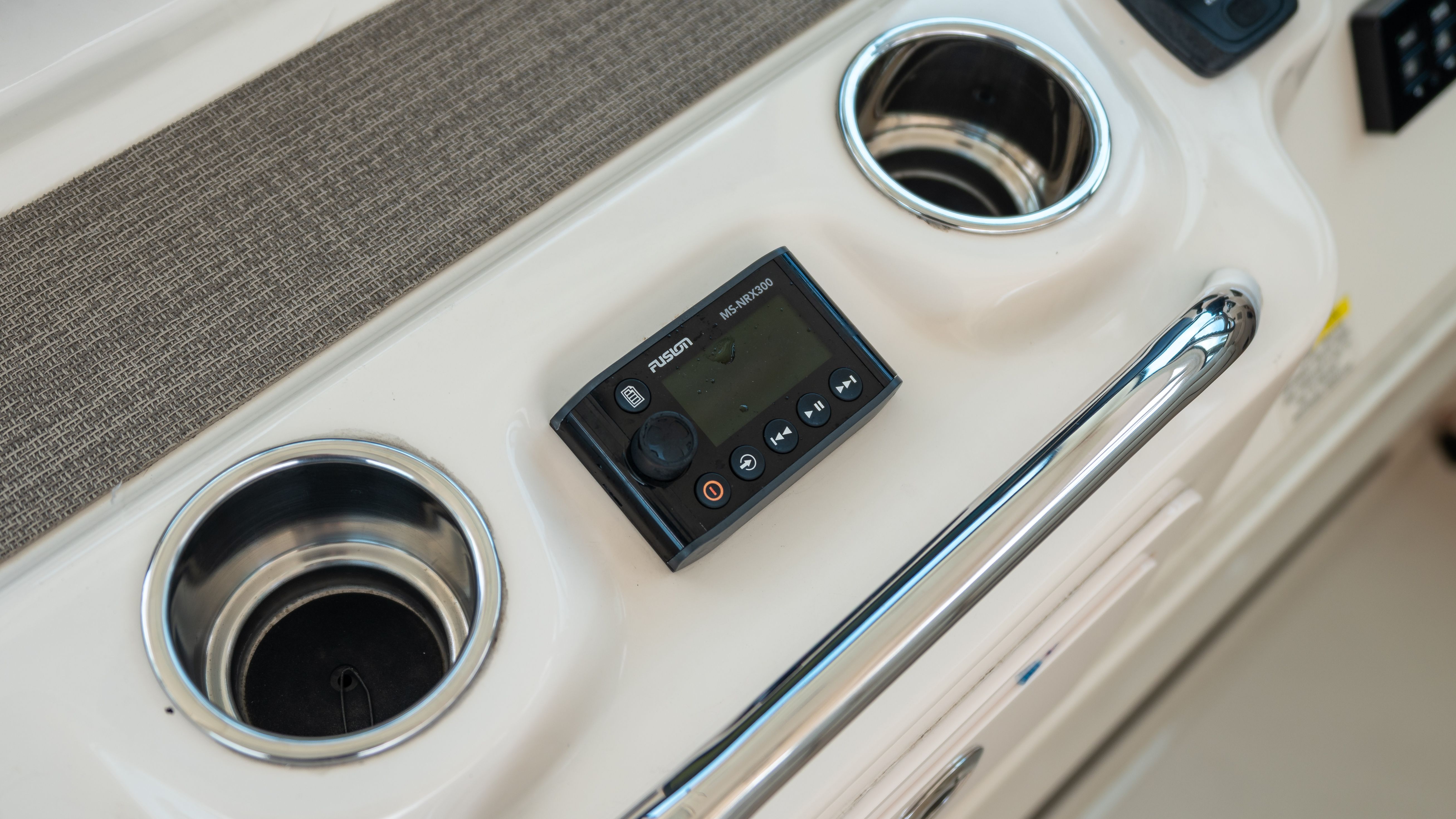 Close-up of a boat console area with cup holders and a control unit.