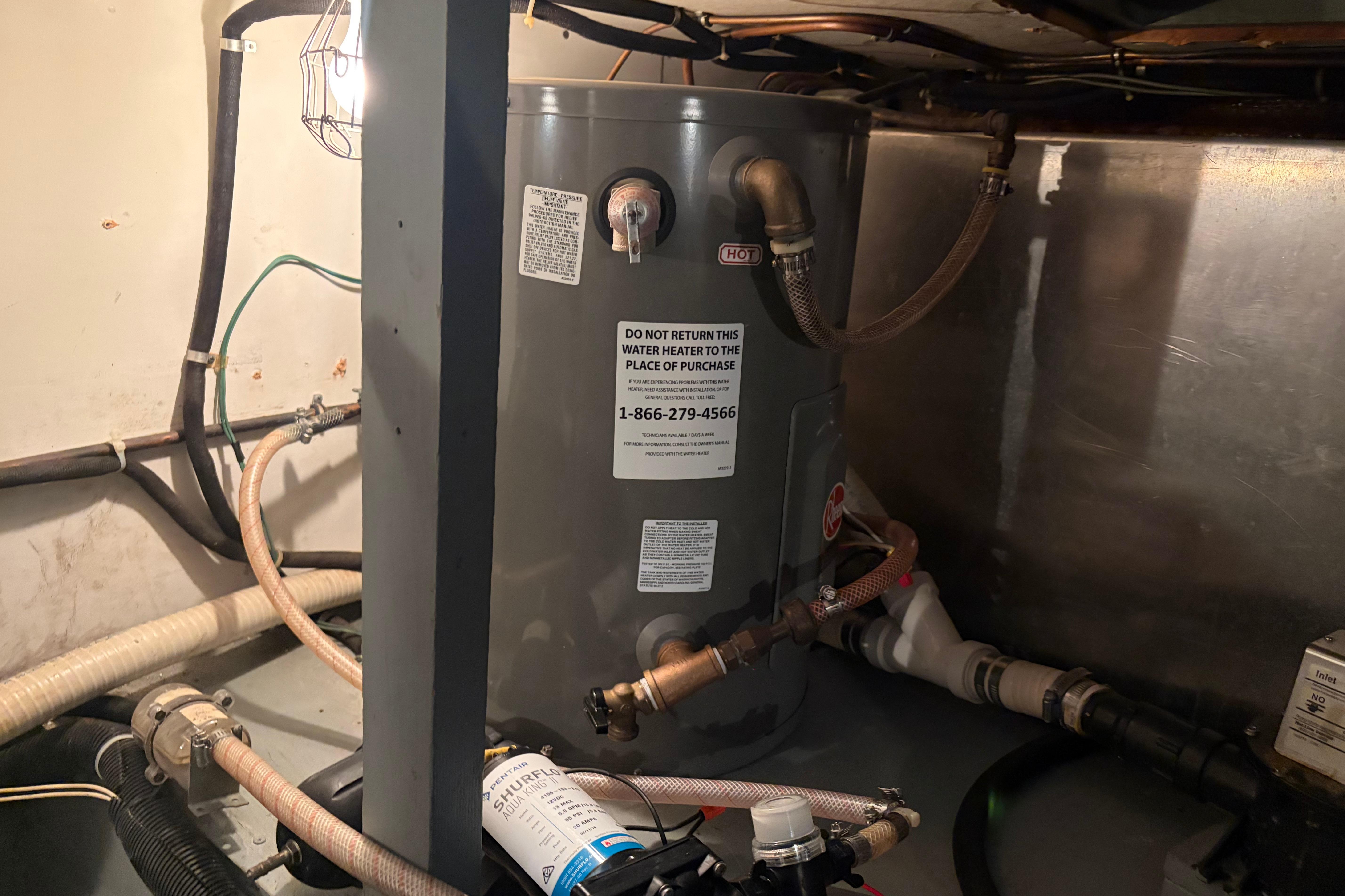 Water heater in 1971 Chris-Craft 42 Commander engine room, surrounded by pipes and wiring.