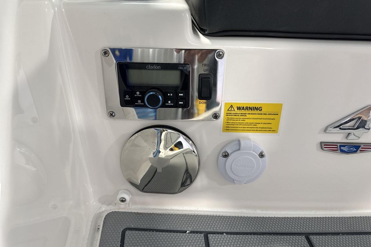 Close-up of a boat panel featuring a Clarion audio system and warning labels.