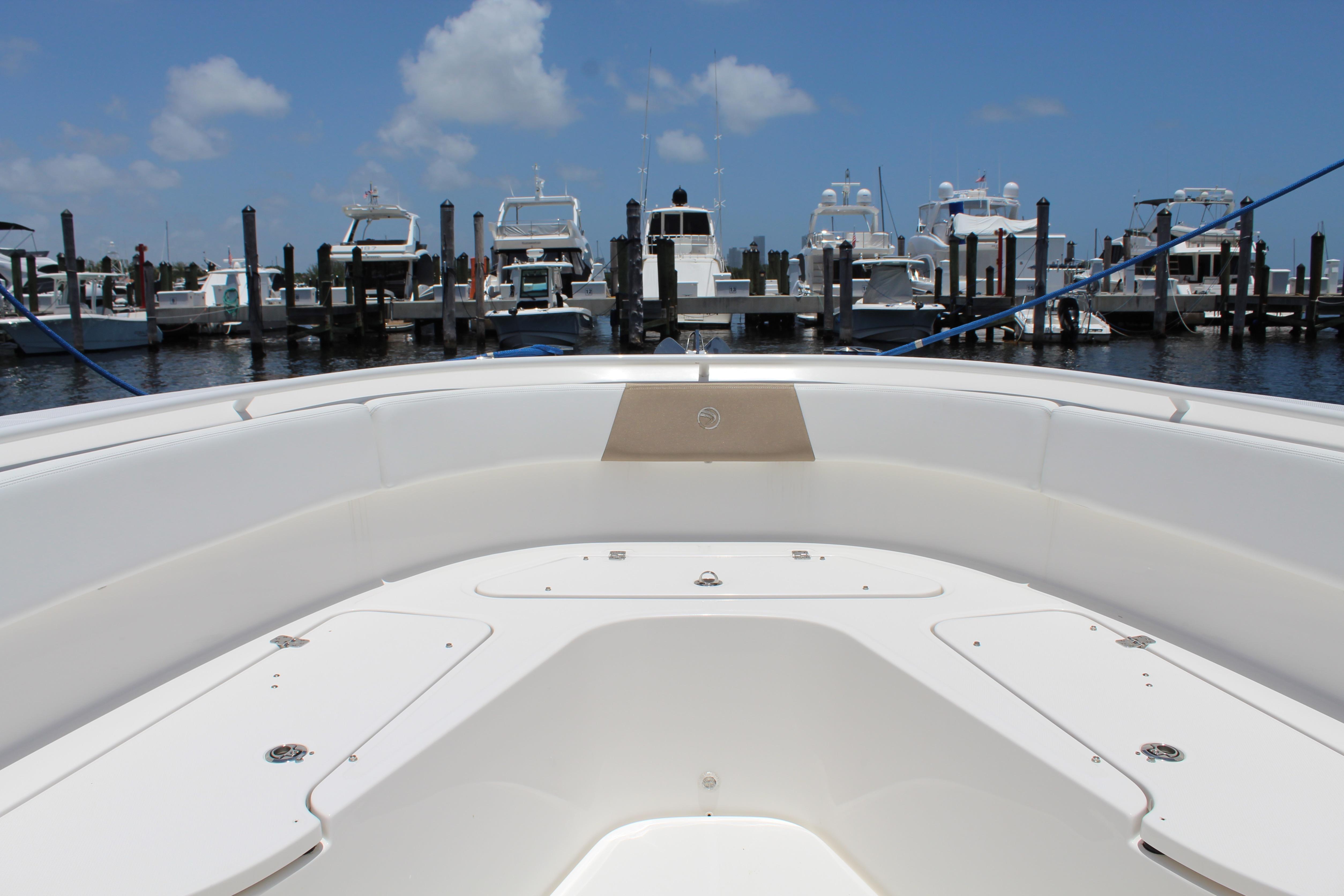 Bow view of 2016 Edgewater 370CC boat docked at marina under blue sky.
