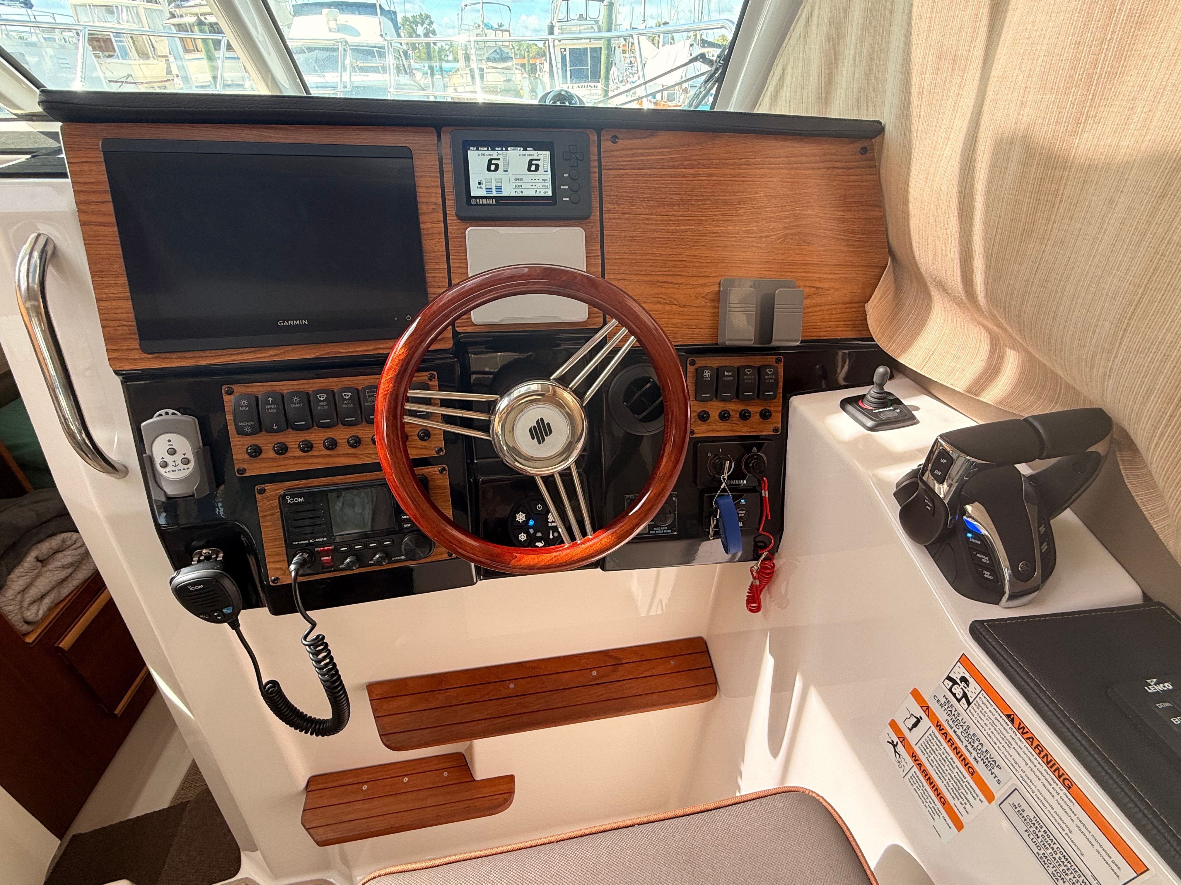 Helm of the Cutwater C-228 with wood paneling and modern instruments.