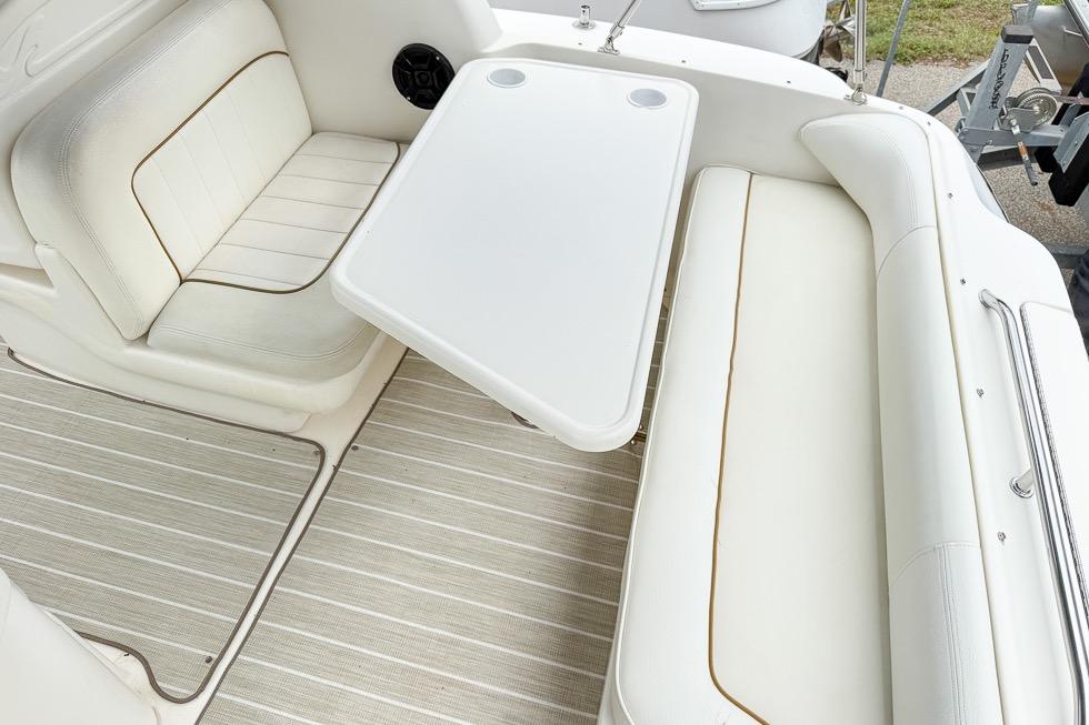 Interior seating area of 1999 Sea Ray 290 Sundancer boat with white upholstery and table.